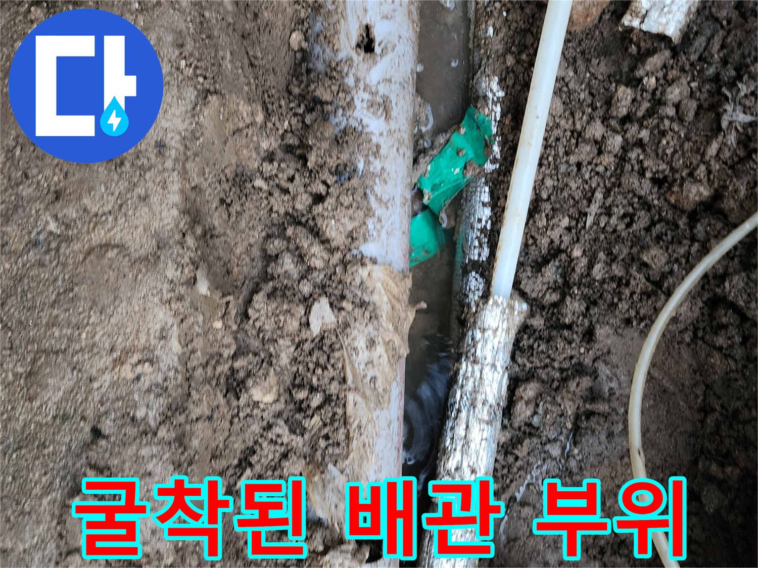 흙과 함께 드러난 흰색 및 초록색 매설 배관