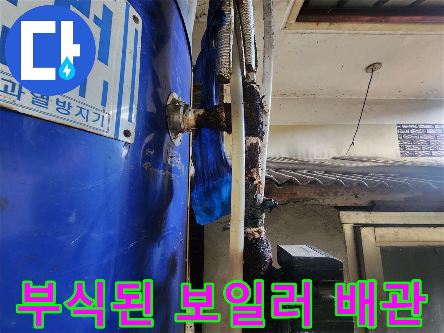 파란색 보일러 본체와 부식된 연결 배관의 모습입니다.