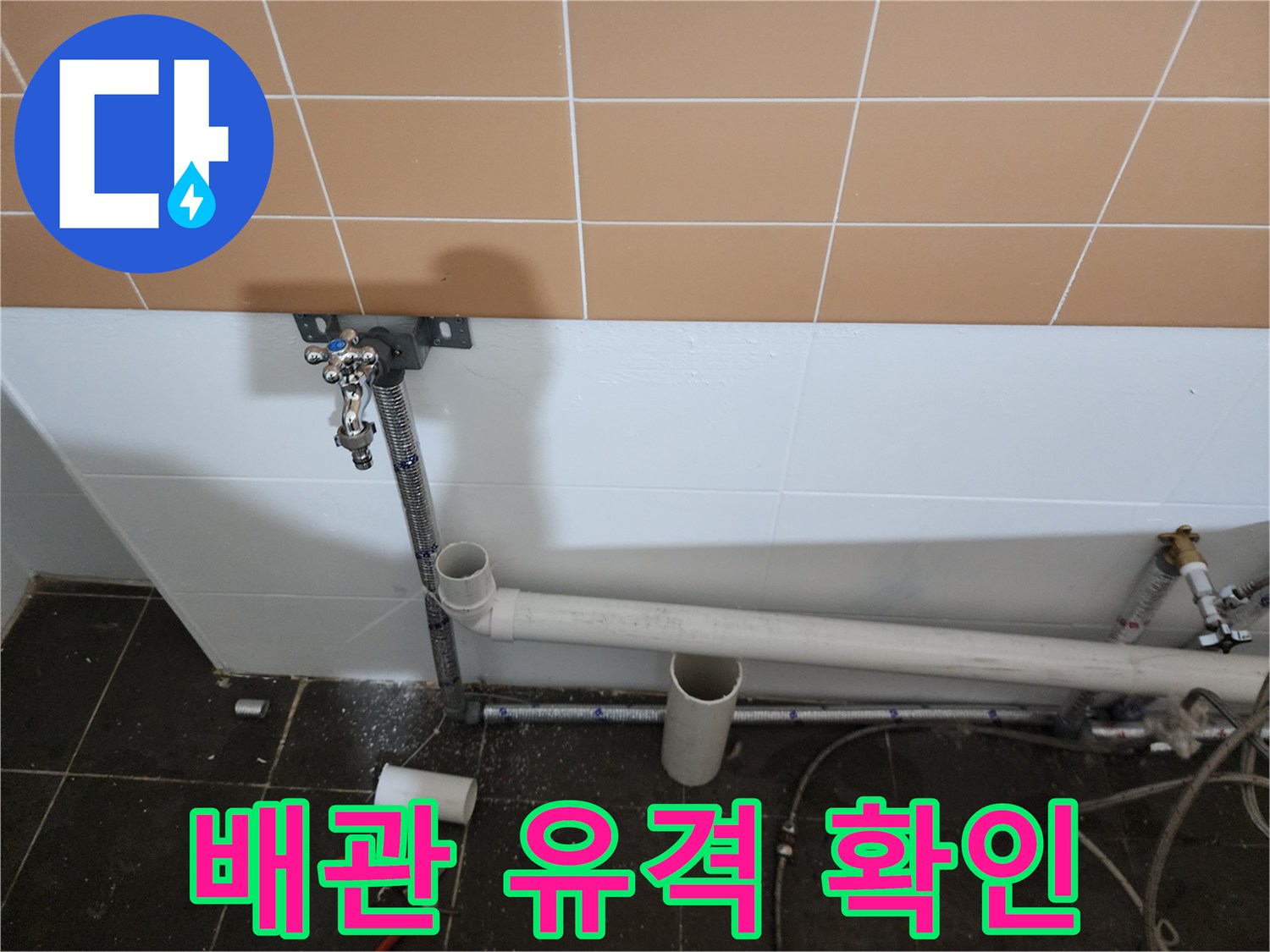 벽면 타일 하단에 설치된 샴푸대용 배관의 연결 상태를 근접 촬영했습니다.