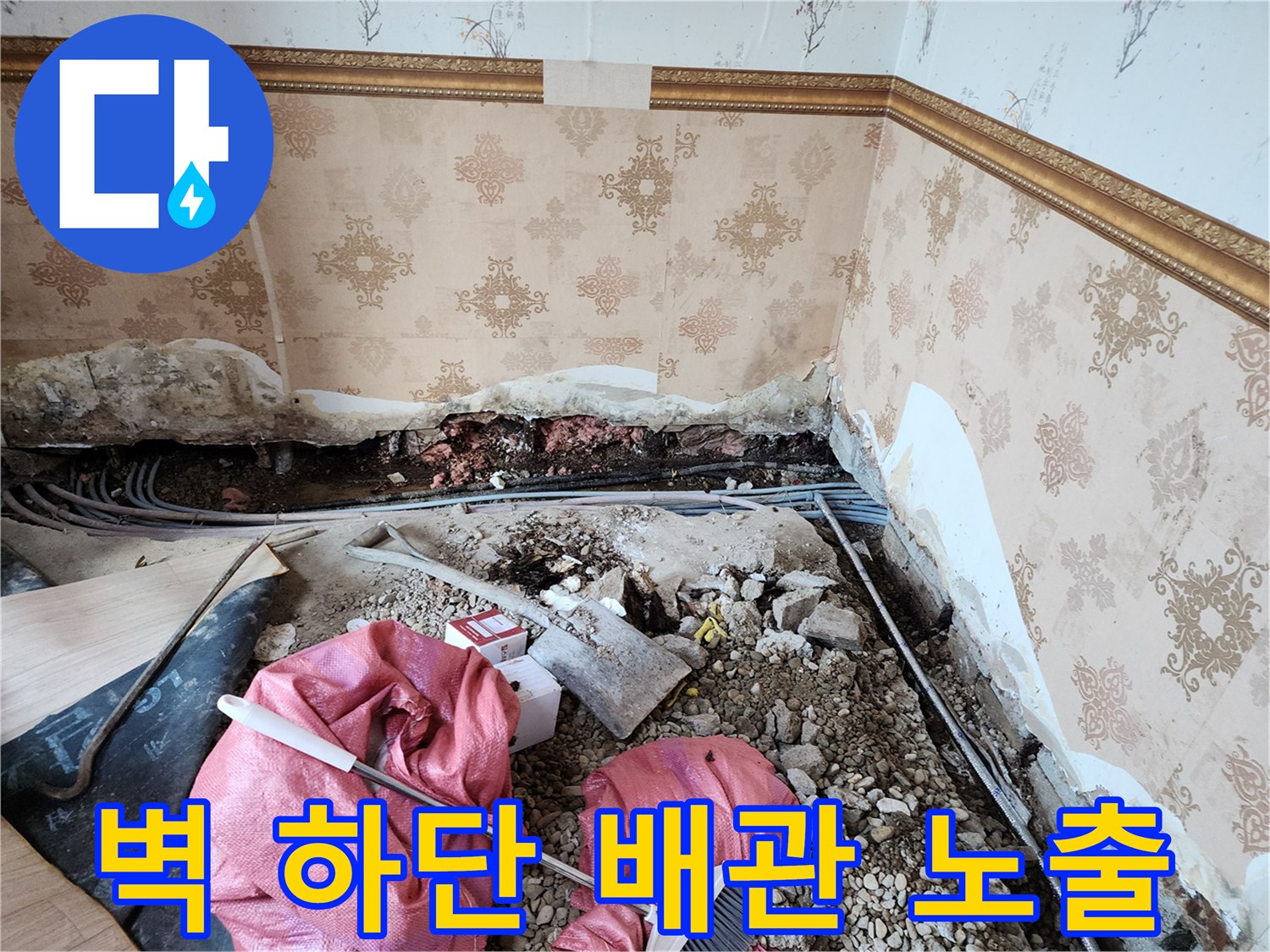 누수 원인 파악을 위해 벽면 하단을 제거하고 배관을 드러낸 현장 사진