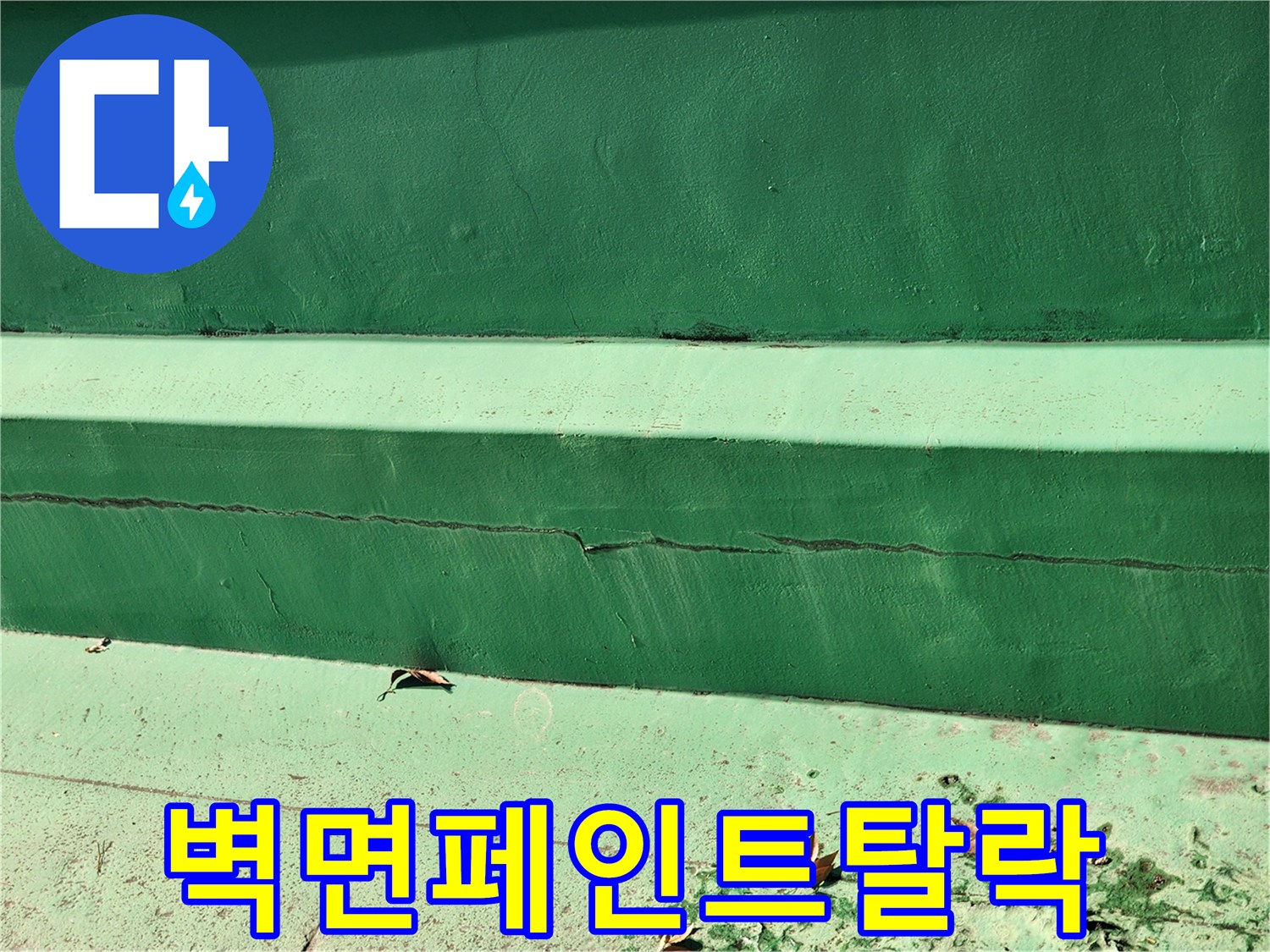 균열과 함께 페인트가 벗겨져 나간 녹색 외벽 하단부