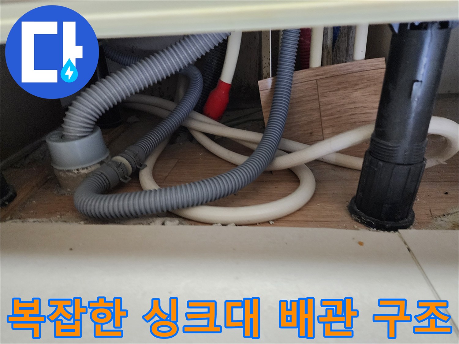 싱크대 아래쪽-여러 갈래로 연결된 배수 호스와 수직 배관의 모습