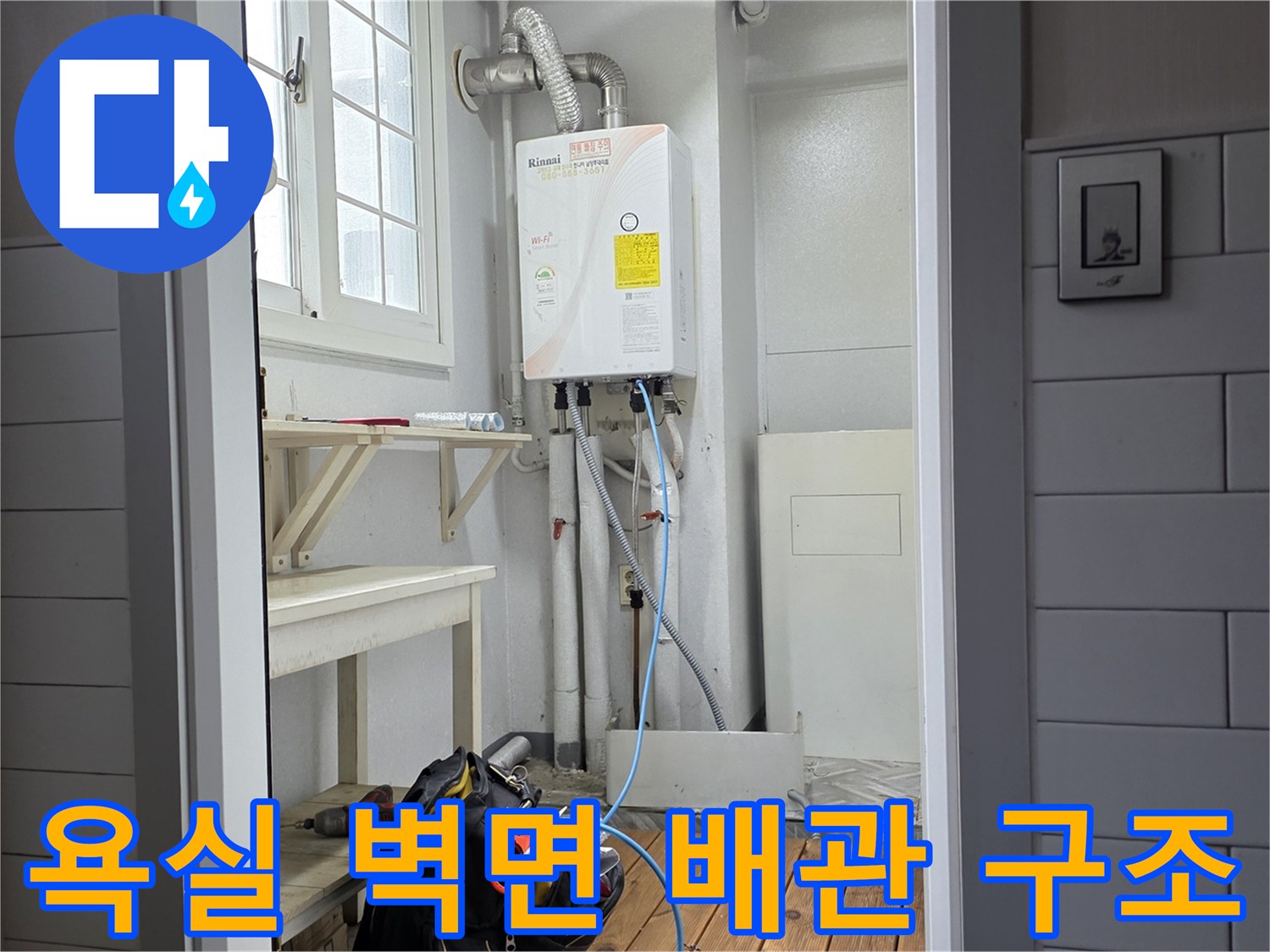 화장실 벽면에 노출된 온수 분배기와 연결 배관의 모습