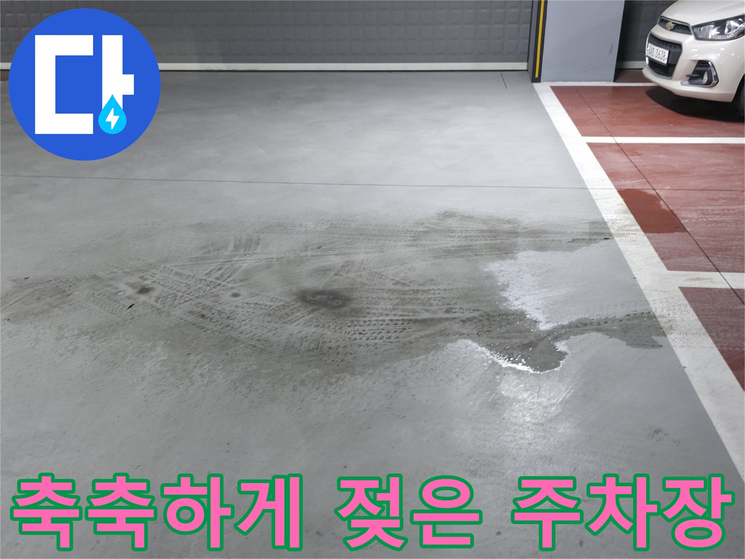 물기가 넓게 퍼져 있는 주차장 바닥의 모습