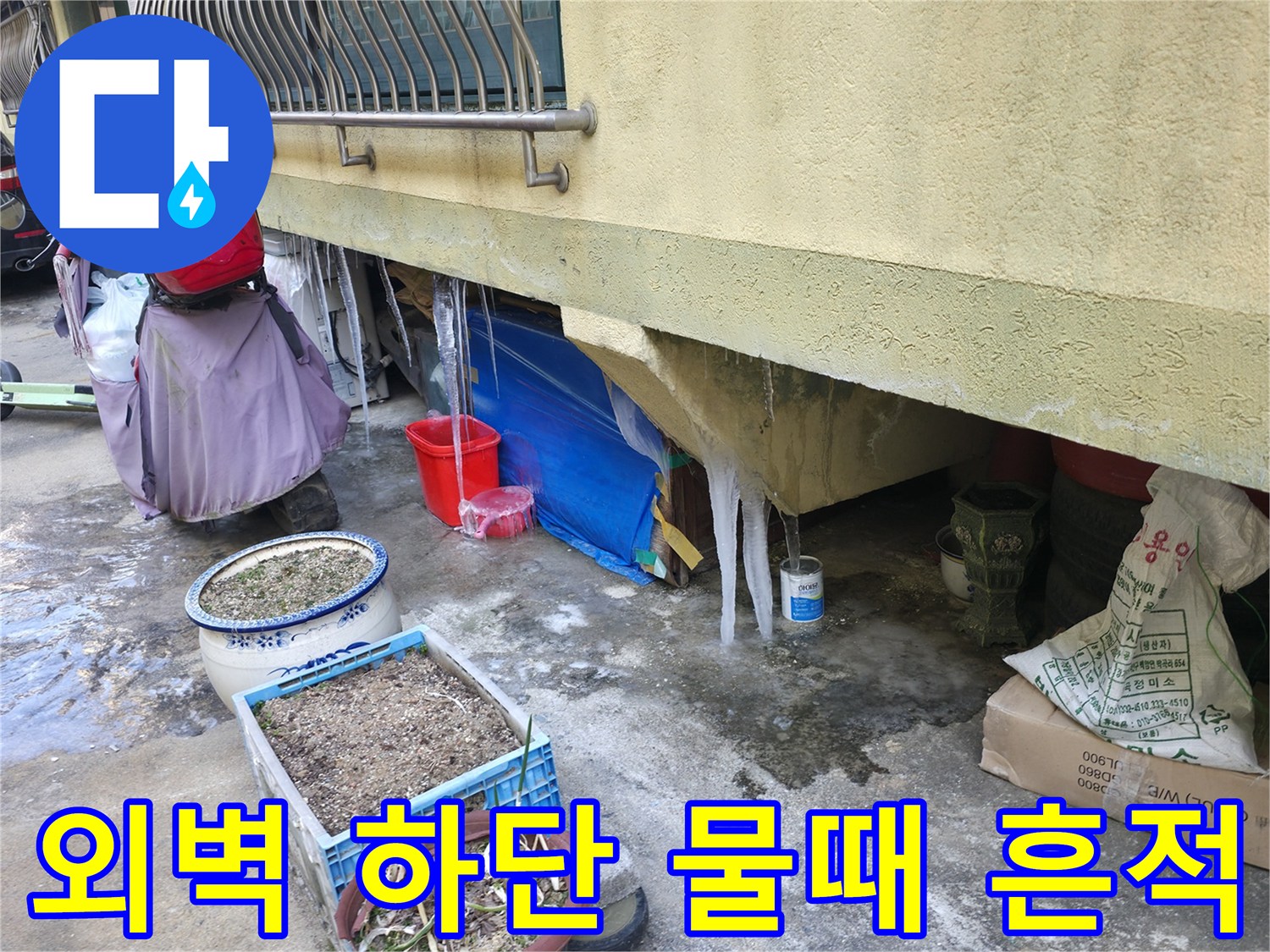 건물 외벽 하단부에 발생한 누수 얼룩과 젖은 바닥