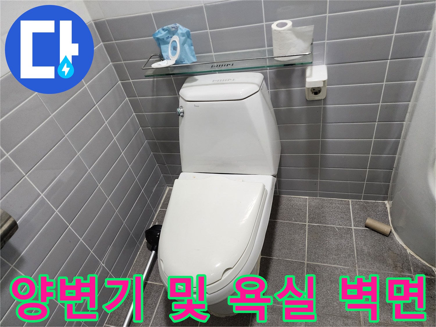깨끗하게 정돈된 화장실 내부의 양변기와 회색 타일 벽면 사진입니다.