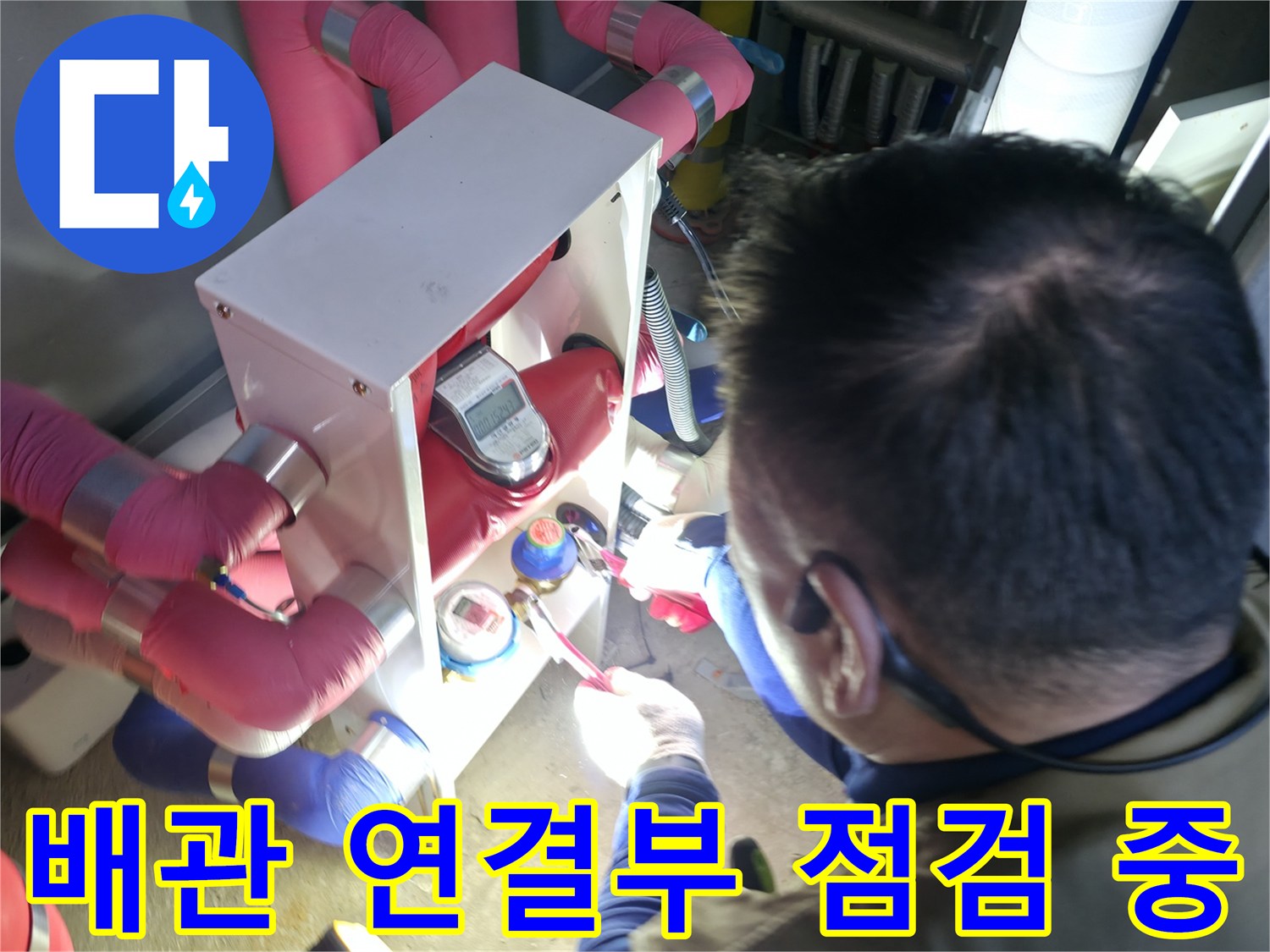분홍색 보온재가 감긴 배관과 금속 밸브 장치를 점검하는 장면