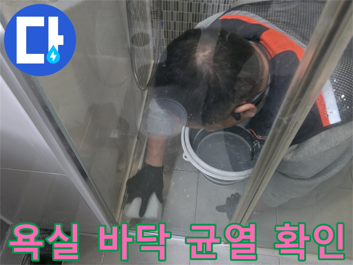 작업자가 샤워실 바닥의 물샘 흔적을 찾기 위해 내부를 살피고 있습니다.