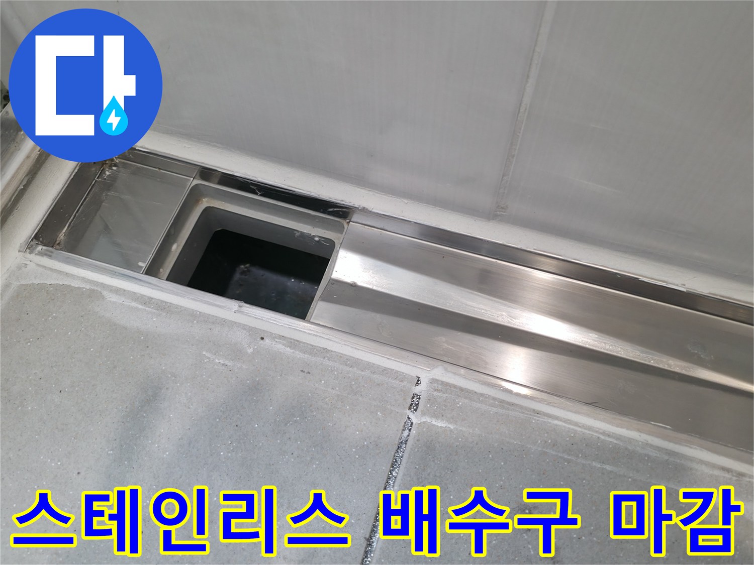화장실 바닥 배수구의 스테인리스 트렌치와 주변 타일 모습입니다.