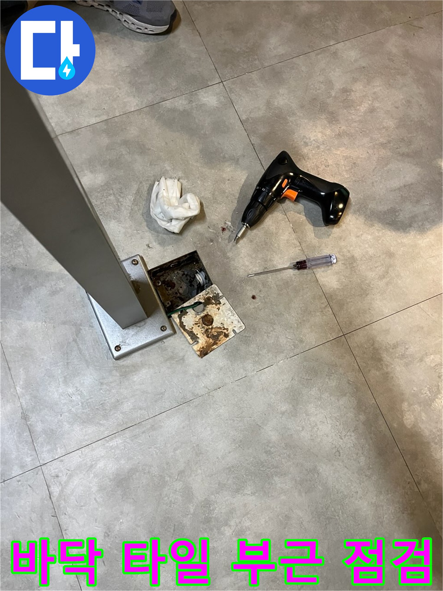 오염된 바닥 타일과 점검용 드라이버의 근접 사진
