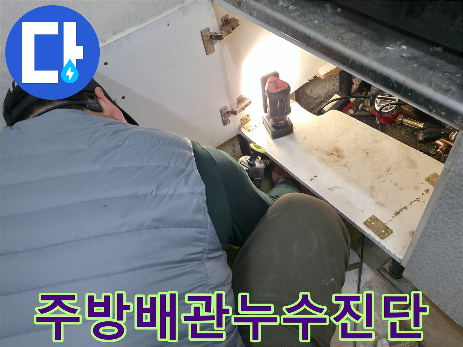 싱크대-내부-조명을-사용하여-배관-연결부를-살피는-모습