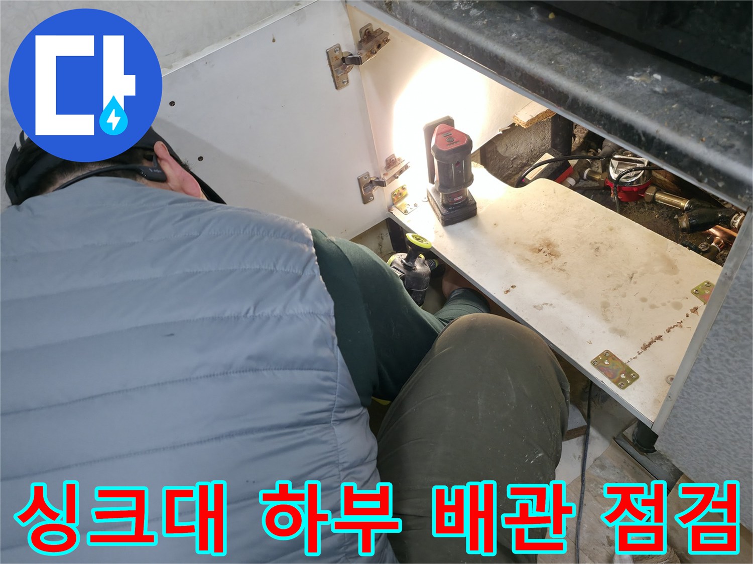 조명을-사용하여-싱크대-하단-배관을-점검하는-장면
