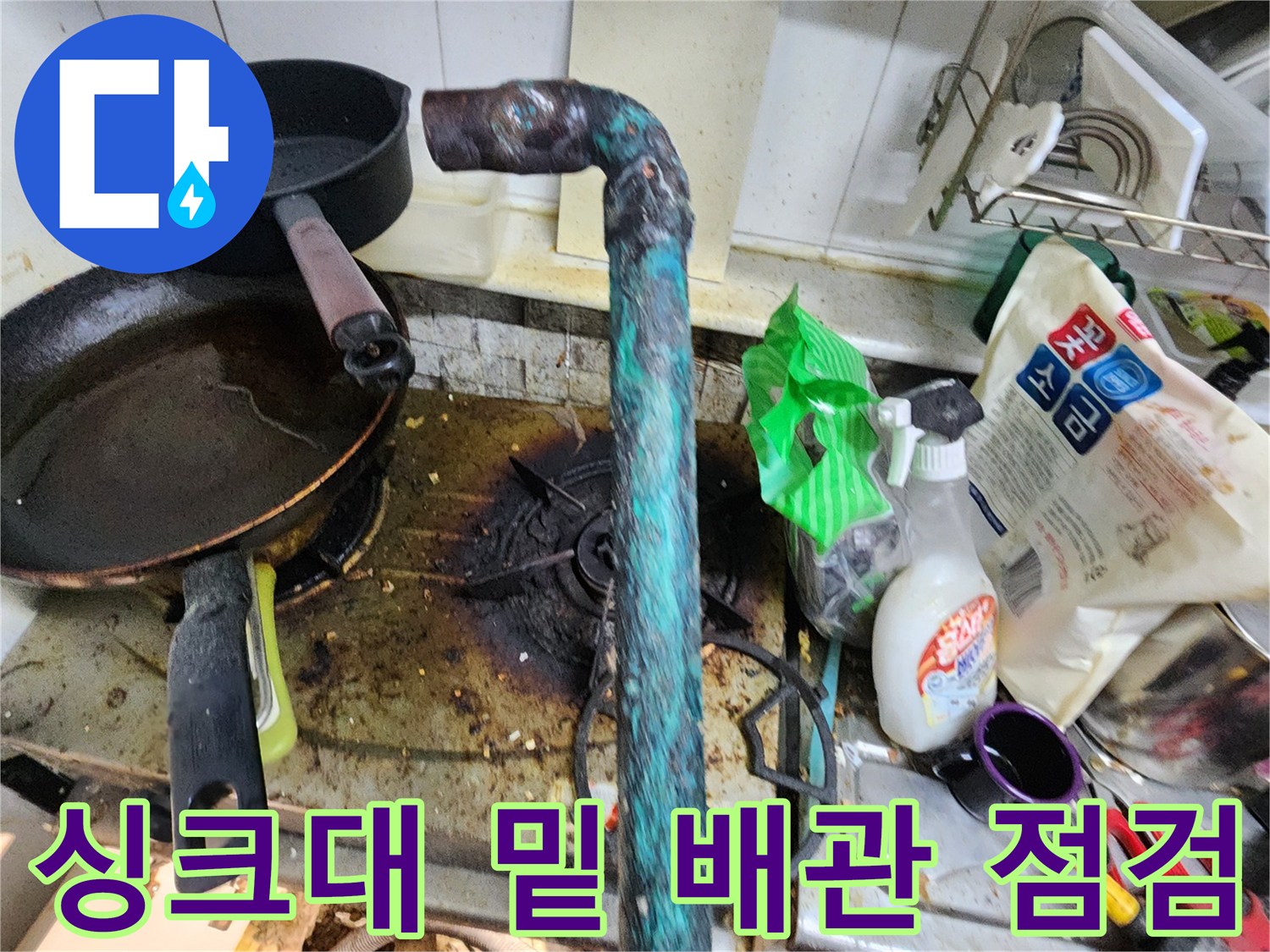 주방 싱크대 하단부에 위치한 부식된 금속 배관