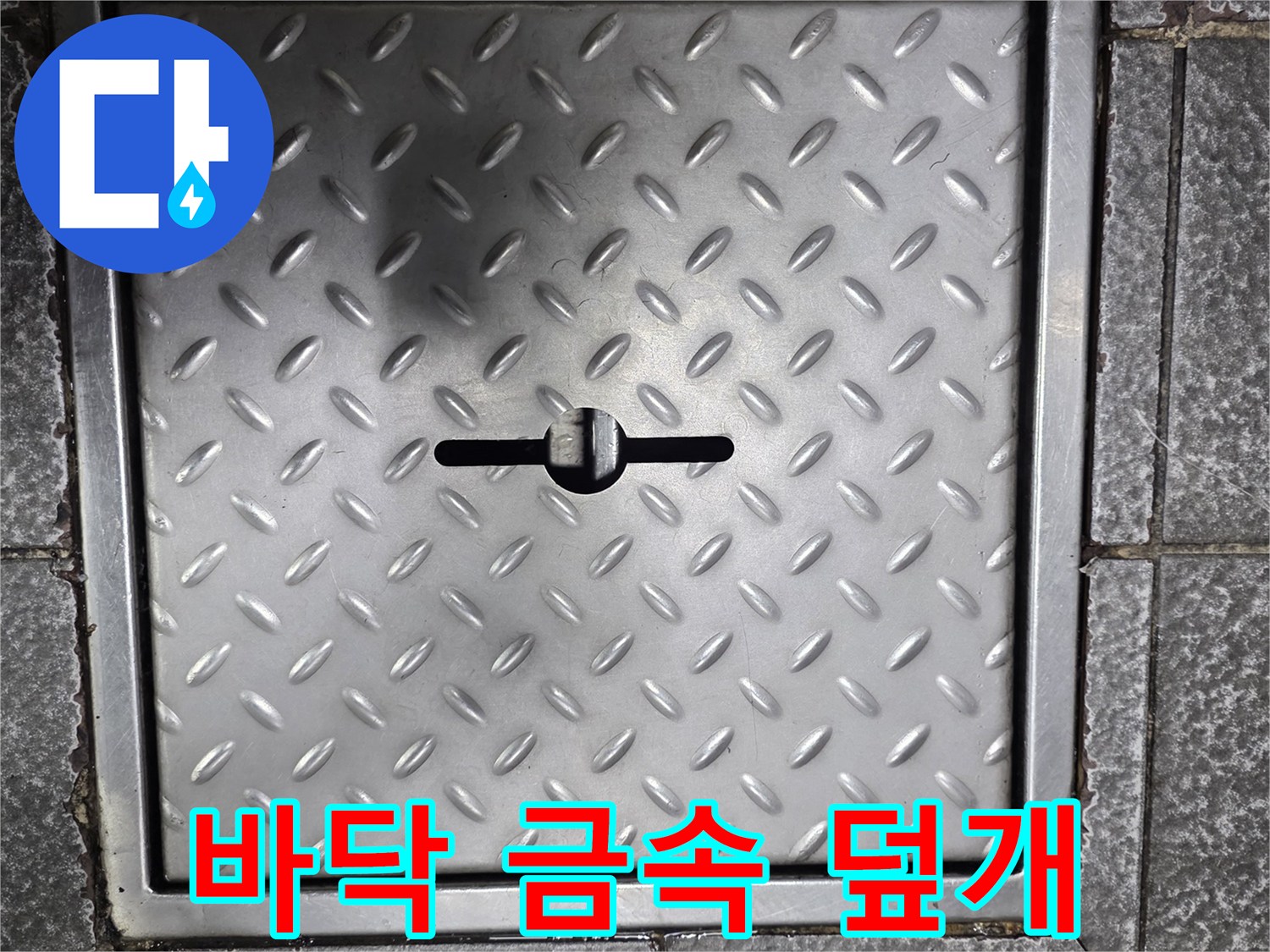 체크 무늬가 새겨진 사각형 형태의 금속 점검구 덮개