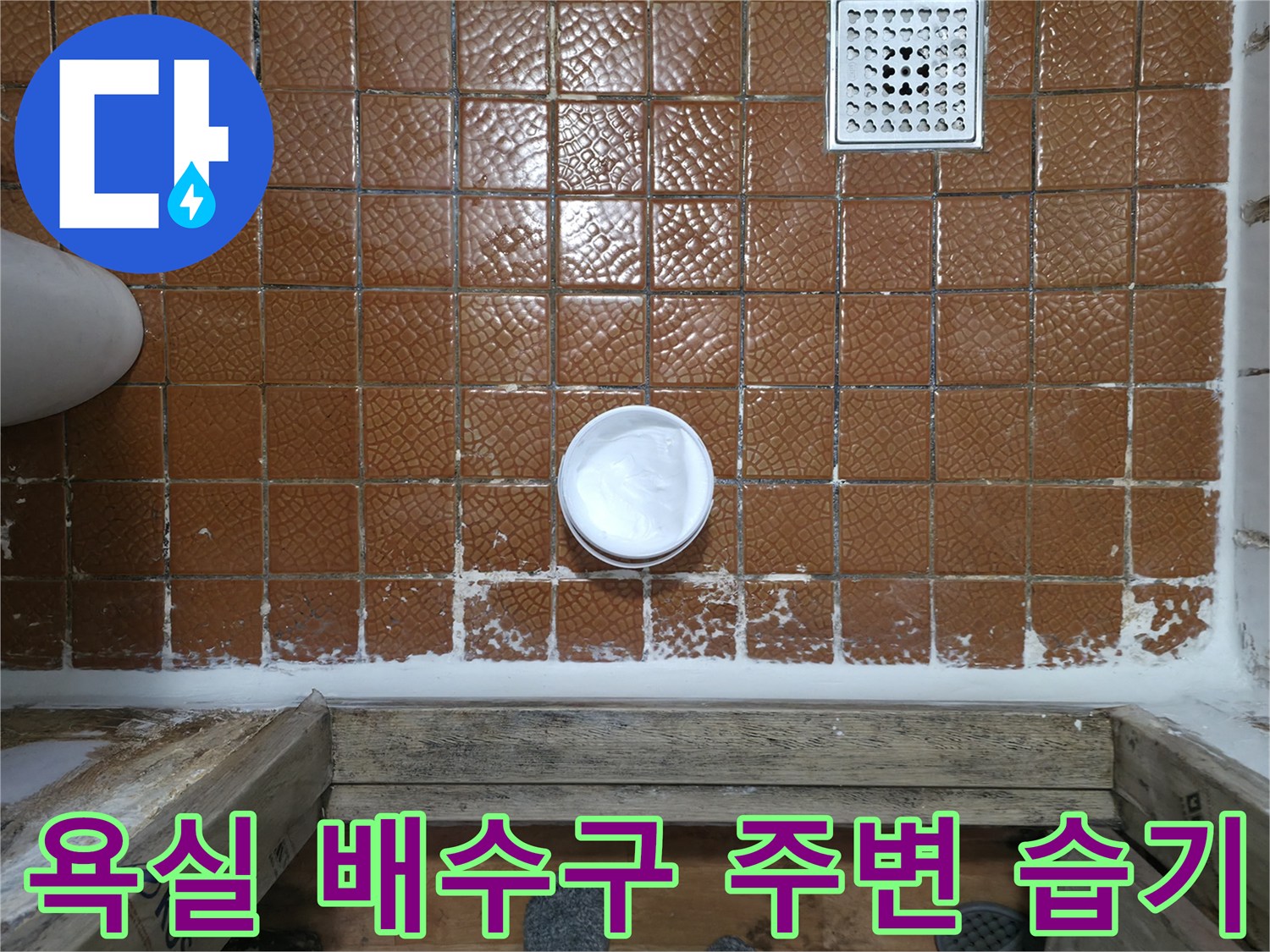 갈색 타일 벽면에 나타난 배수구와 물기 흔적