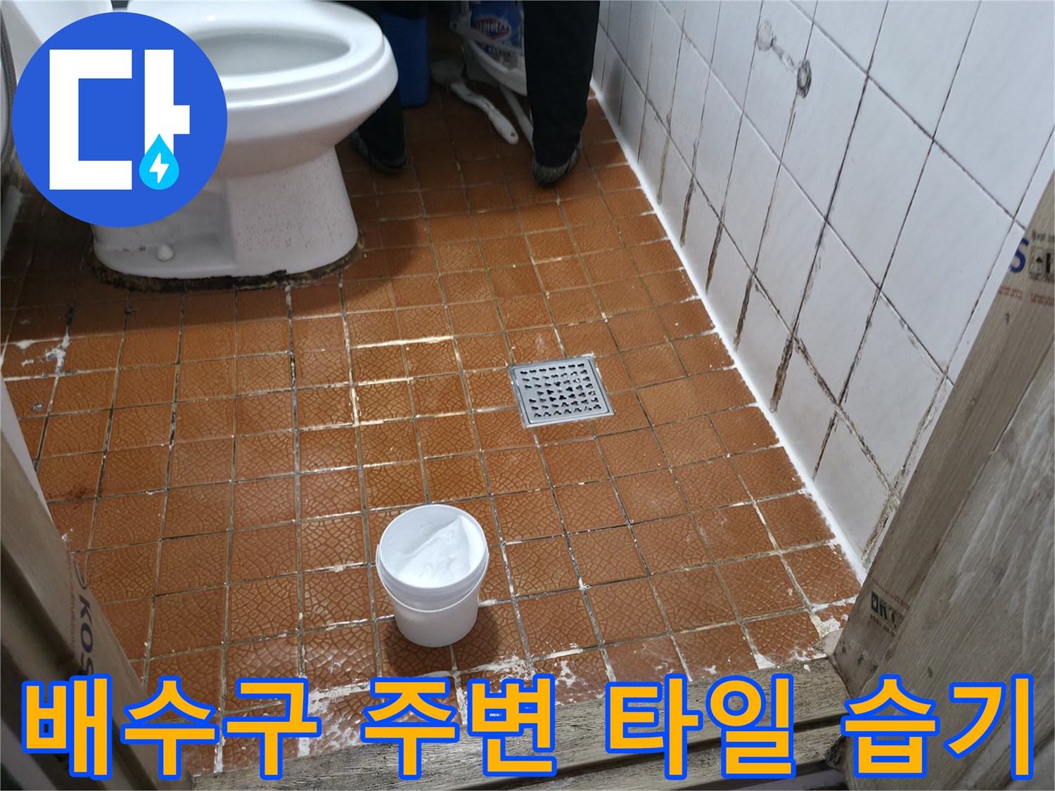 욕실 바닥 갈색 타일의 배수구와 변기 근처 모습