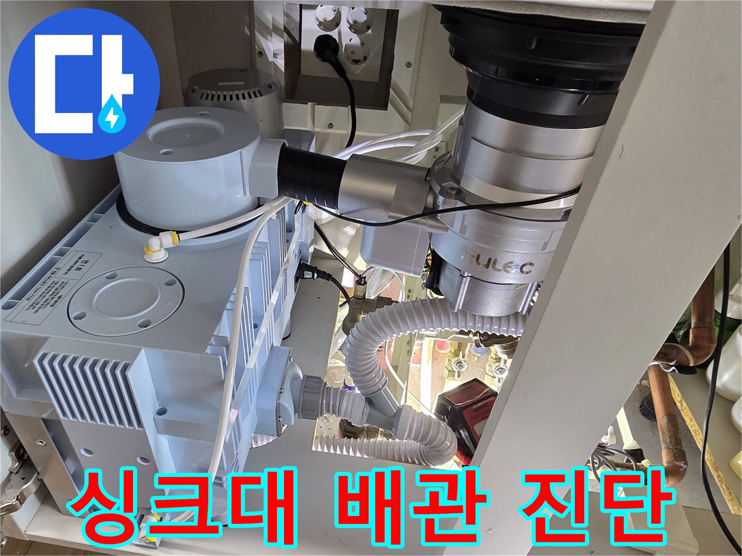 주방 싱크대 아래 복잡한 배관 구조와 압력 측정 장비의 모습