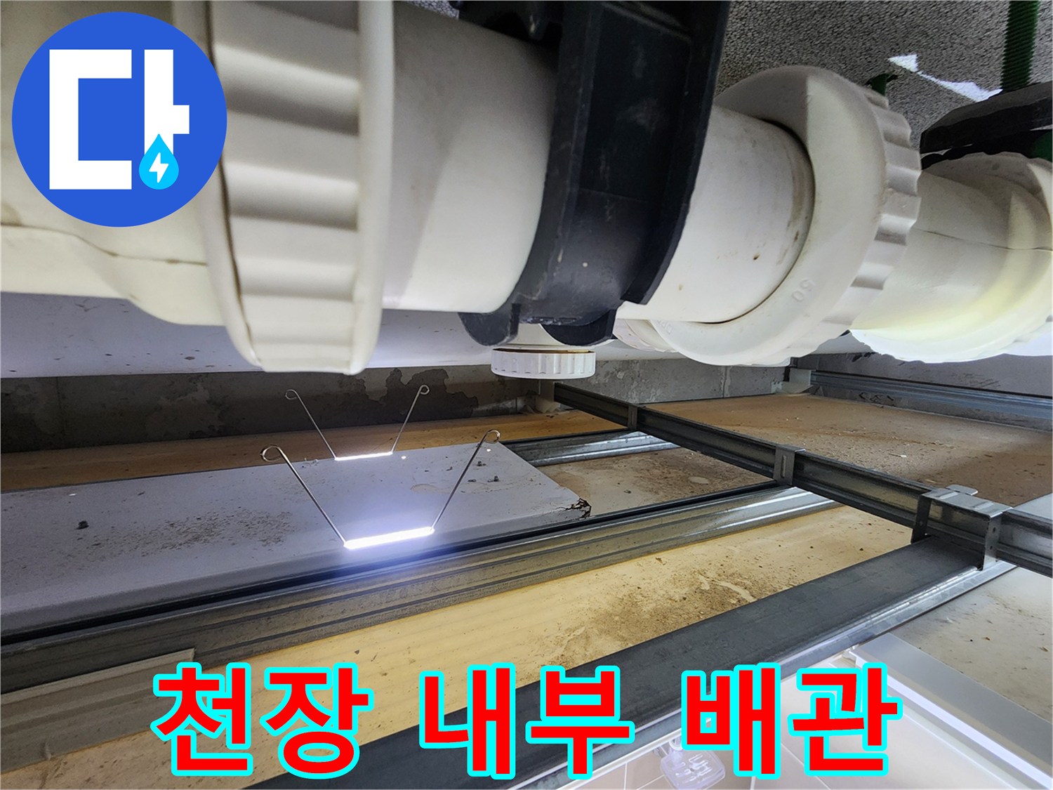 천장 점검구 안쪽의 흰색 PVC 오수 배관 구조물