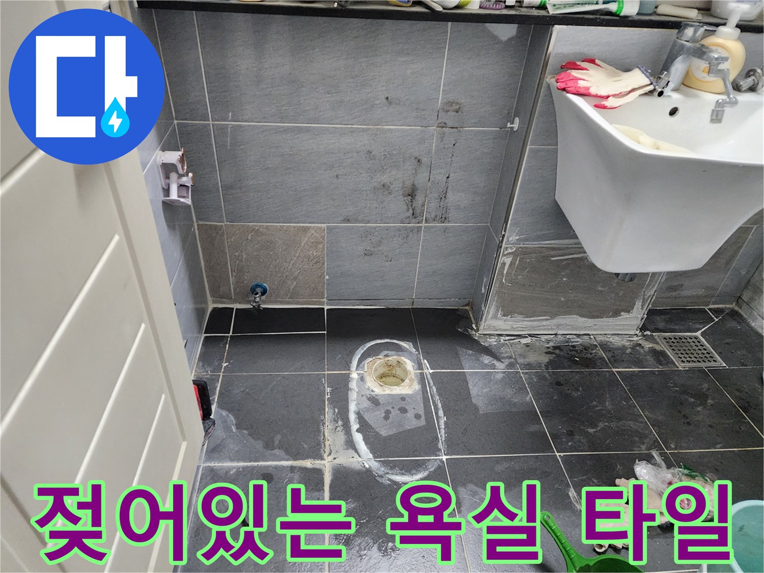 변기 배관 주변의 젖은 타일과 습기가 가득한 욕실 바닥 모습