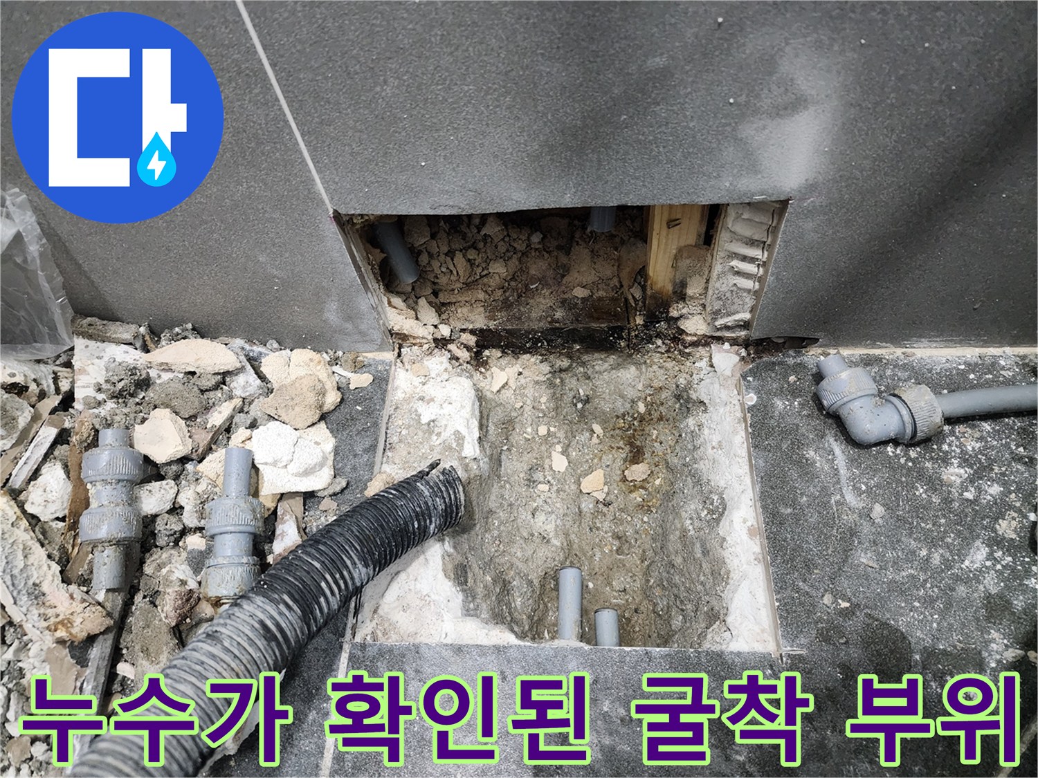 타일 아래 드러난 배관 연결 부품의 누수 상태 사진