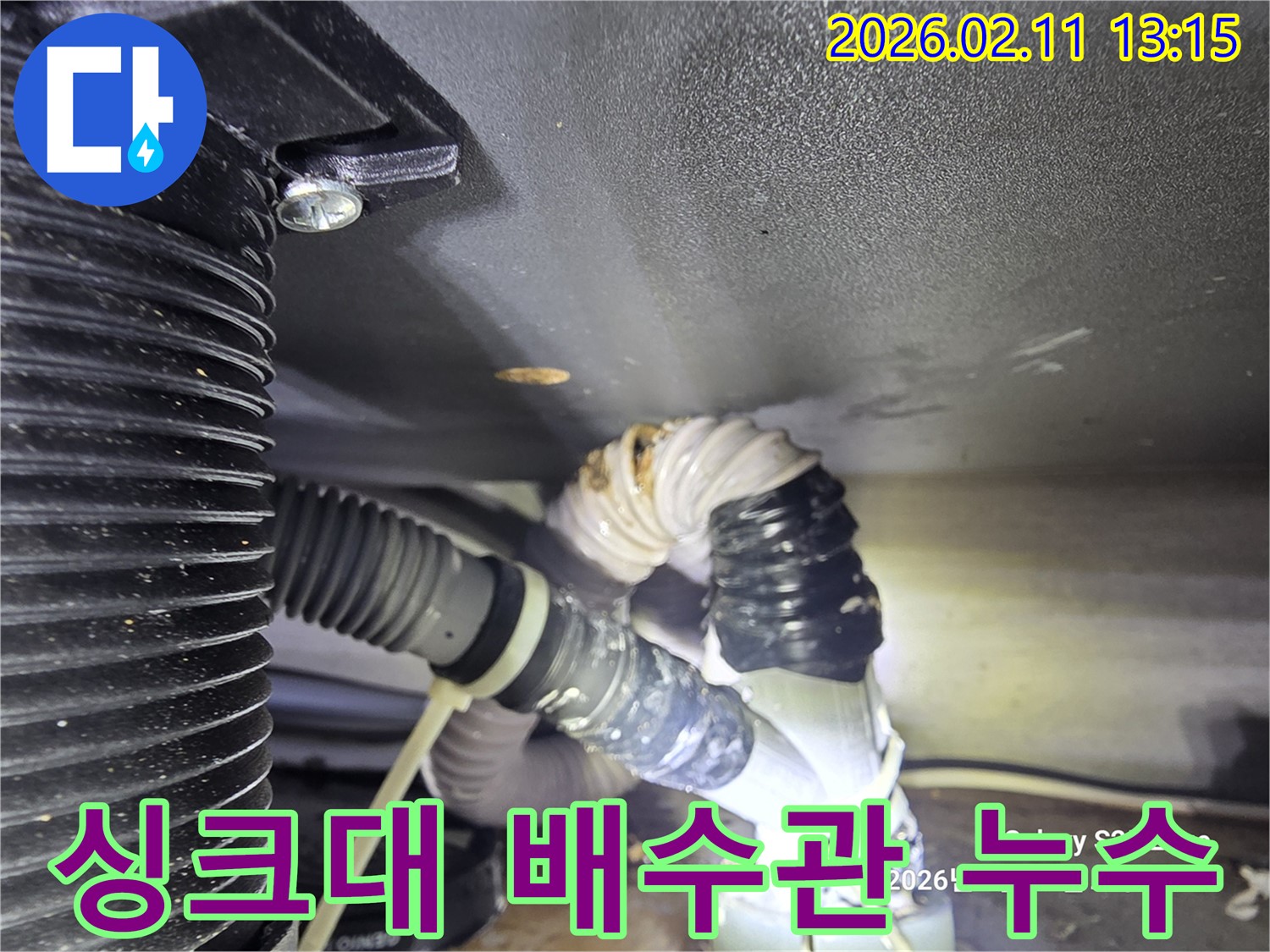 싱크대 하부에서 발생한 배수관 누수 현장을 포착한 이미지입니다-젖은 배관 연결 부위가 명확하게 보입니다