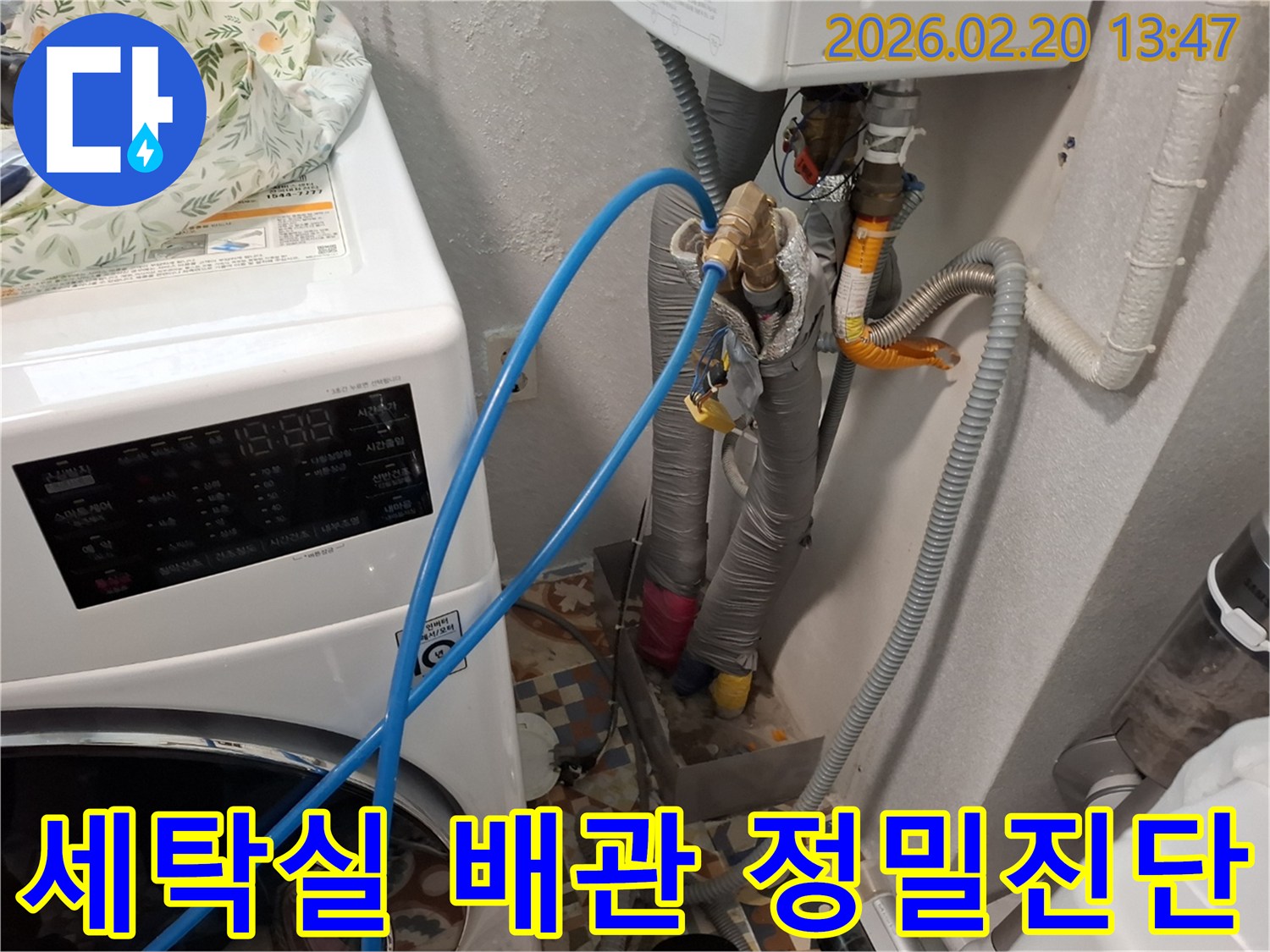 세탁기 옆 복잡한 배관에-누수탐지 장비를 연결하여-정밀 진단을 준비하는 모습
