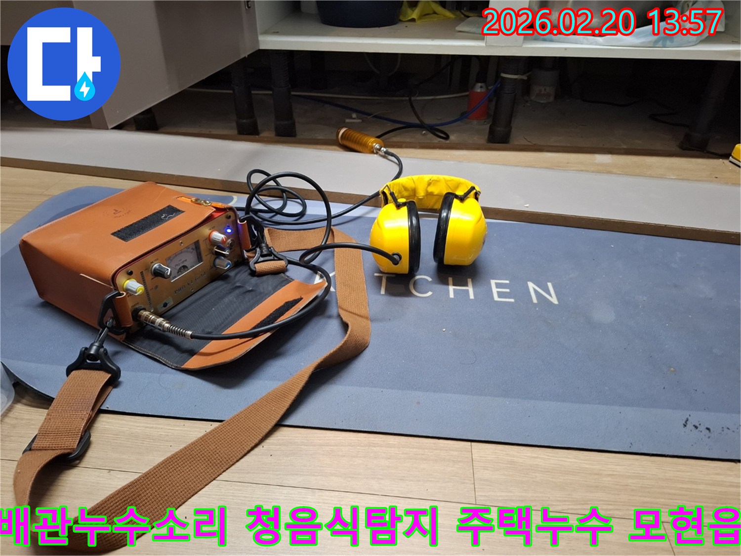 누수 엔지니어가 주방 바닥에 설치된 청음식 탐지 장비로-배관의 미세한 물샘 소리를 듣고 있습니다-정확한 누수 지점 파악을 위한 필수 장비입니다