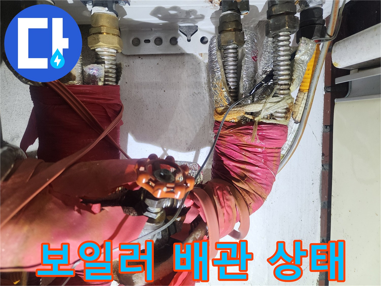 붉은색 보온재와-금속 밸브가 연결된 배관