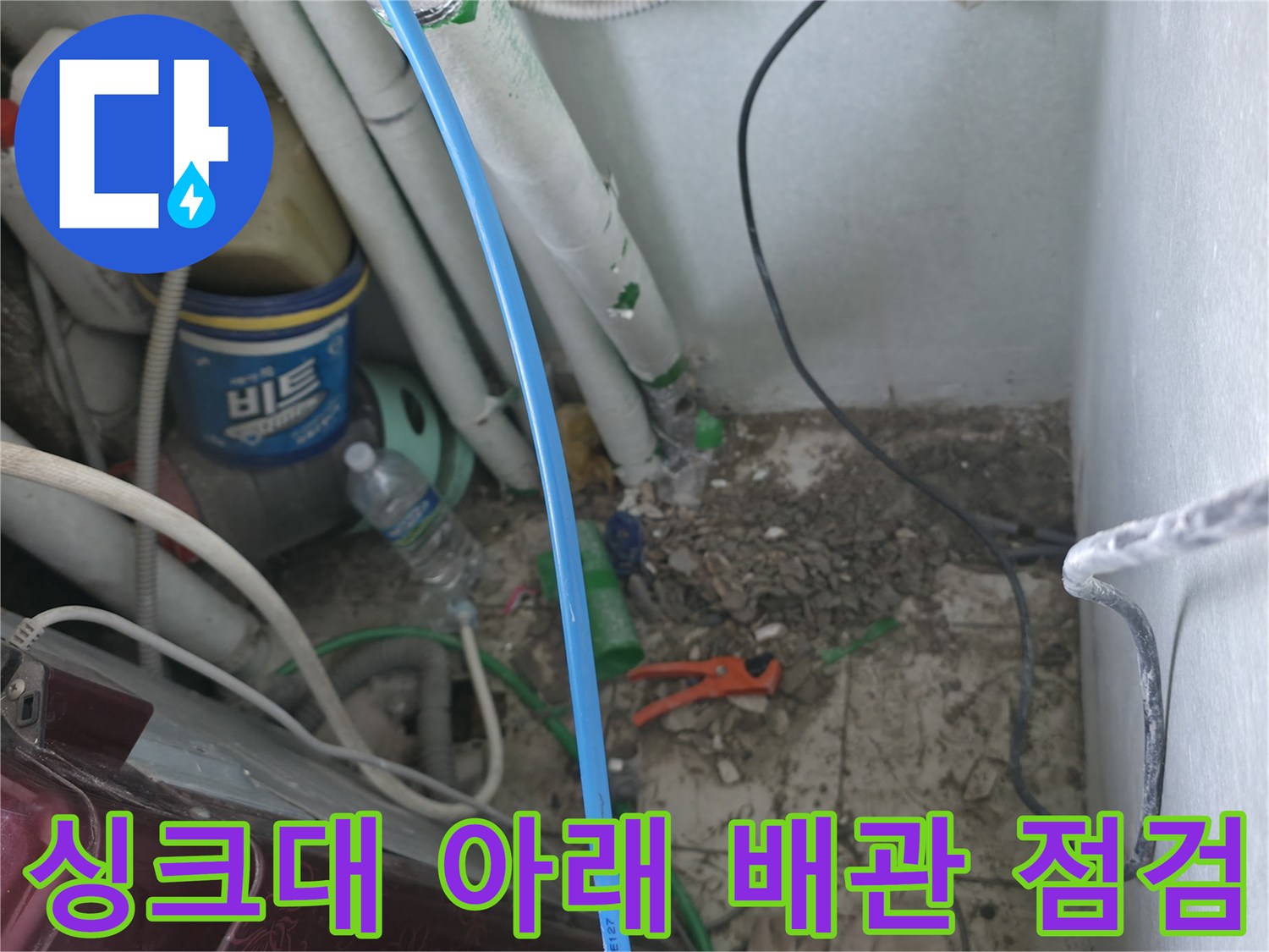싱크대 하부 공간의 배관들과 주변 바닥면 상태를 보여주는 사진입니다