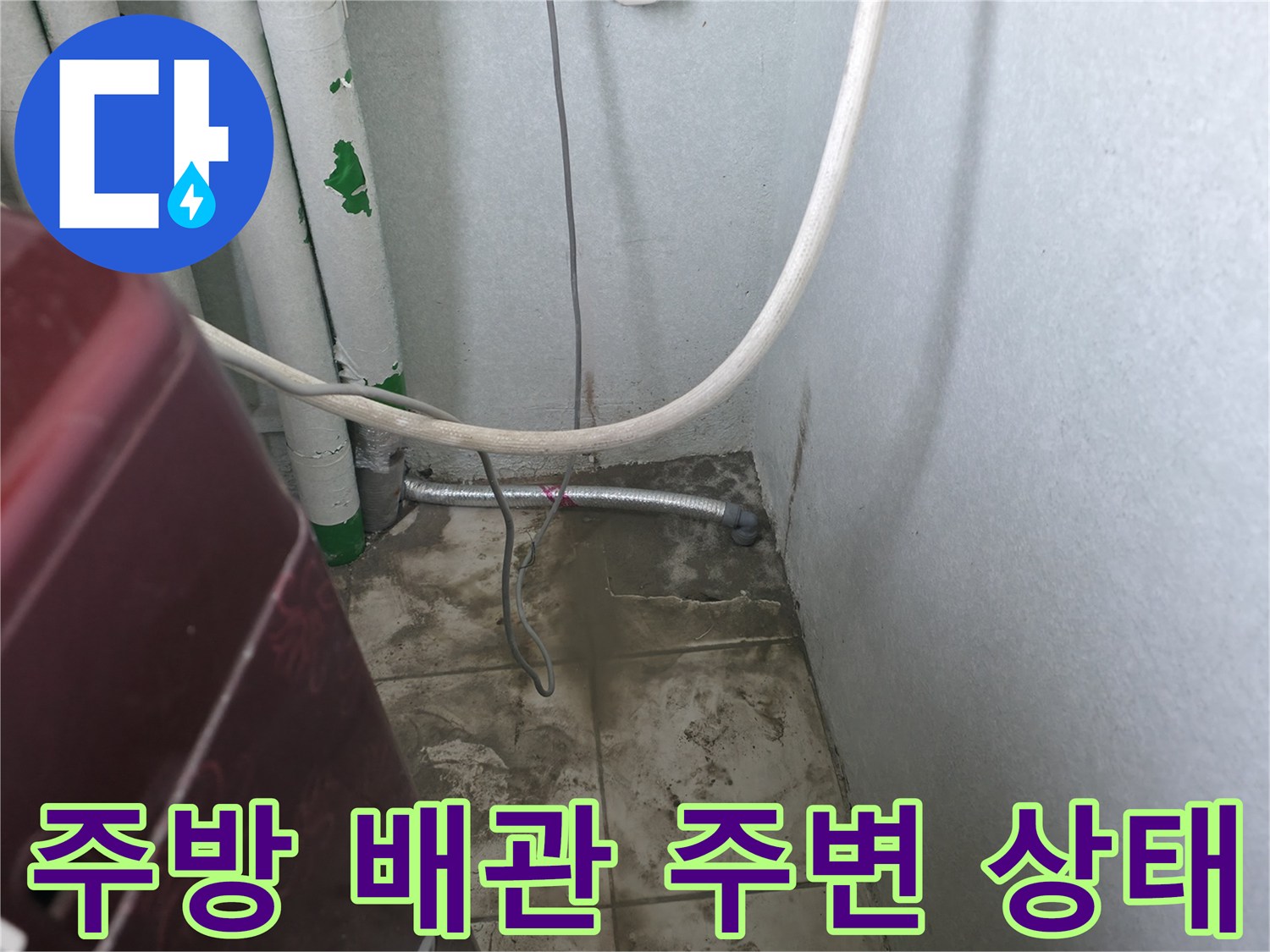 주방 싱크대 하부장 근처의 배관과 벽면 상태를 보여주는 사진입니다.