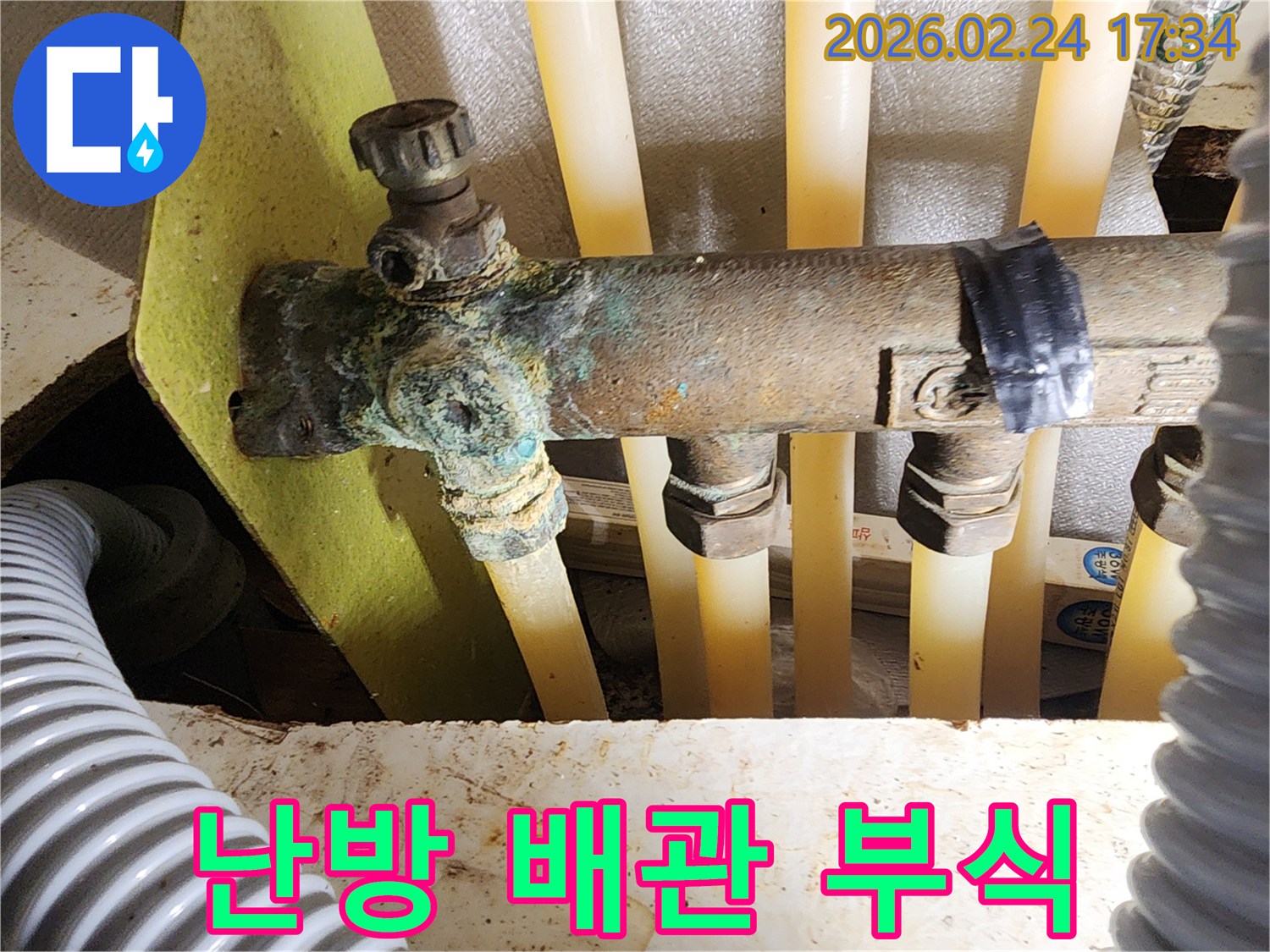 이 이미지는 아파트 난방 분배기의 배관에서-발생한 심각한 부식과-그로 인한 누수 현장을 보여주며-정밀 진단을 통한 해결이 시급함을 나타냅니다.