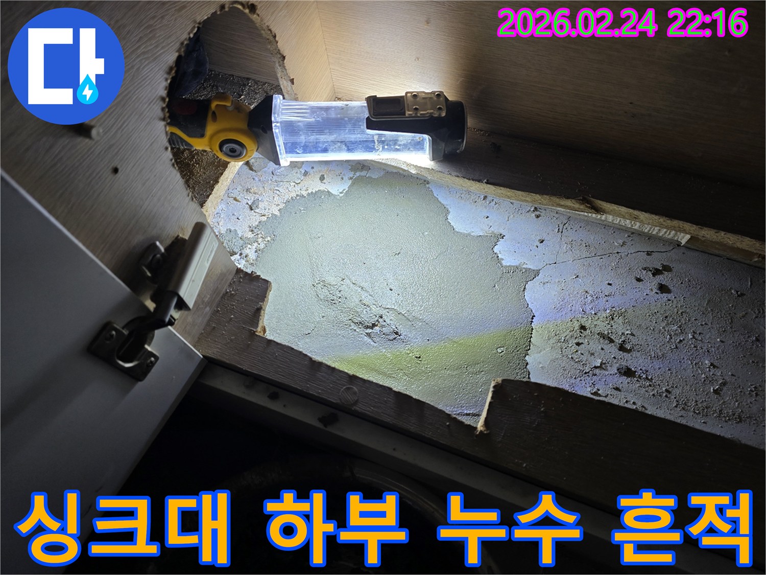 누수-엔지니어가-싱크대-하부-어두운-곳에서-발견된-누수-흔적을-조명으로-밝혀-정밀하게-확인하는-모습