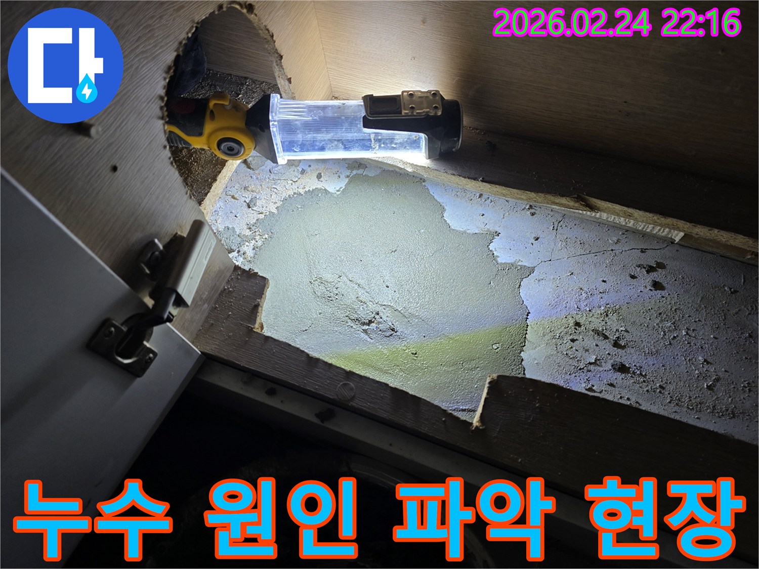 누수-전문가가-어두운-싱크대-하부에서-누수-원인을-파악하기-위해-조명-장비를-사용하여-정밀-조사하는-모습