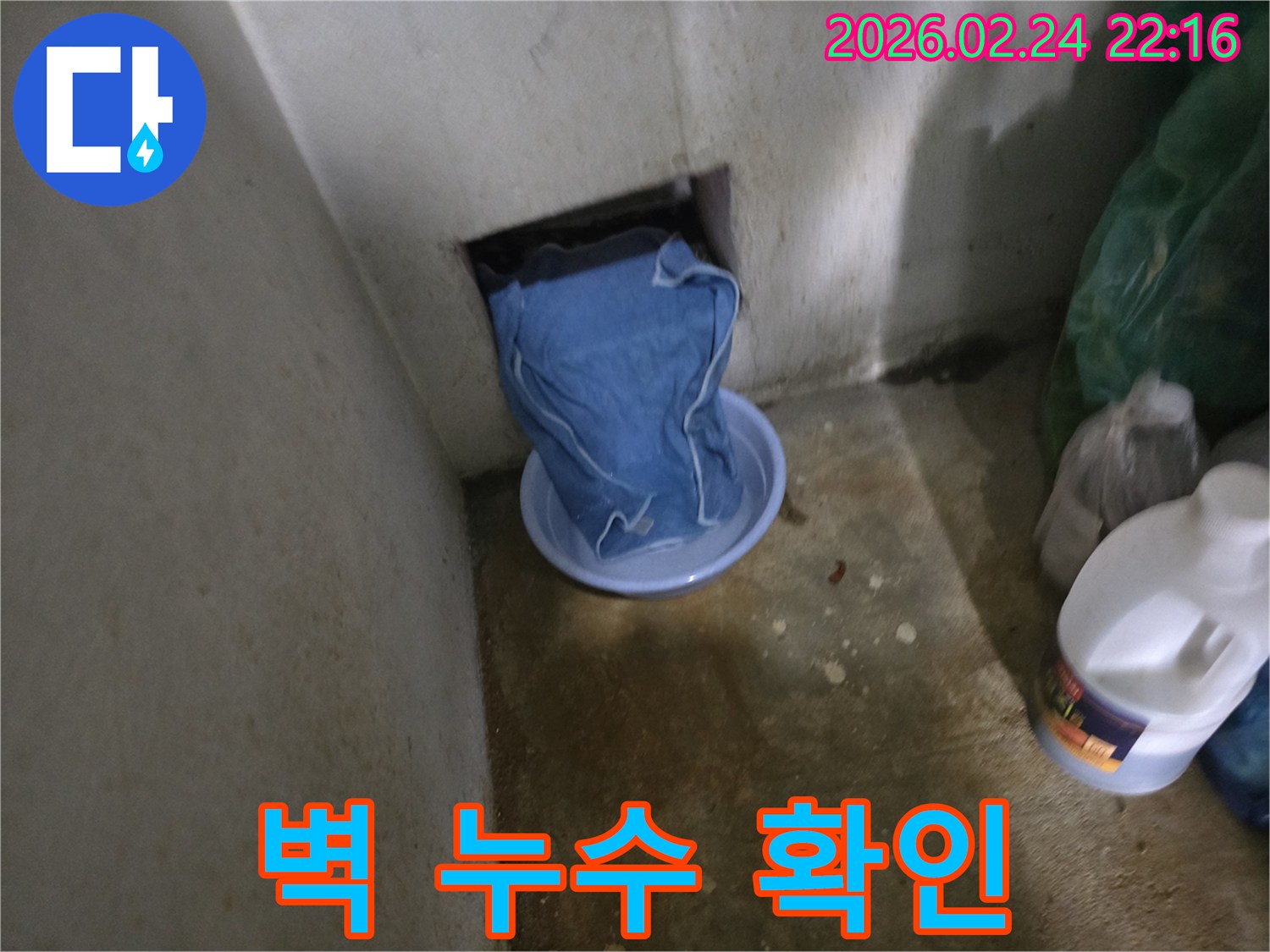 물이 지속적으로 새는 벽 구멍을-천으로 막고-아래에서 물을 받고 있습니다.