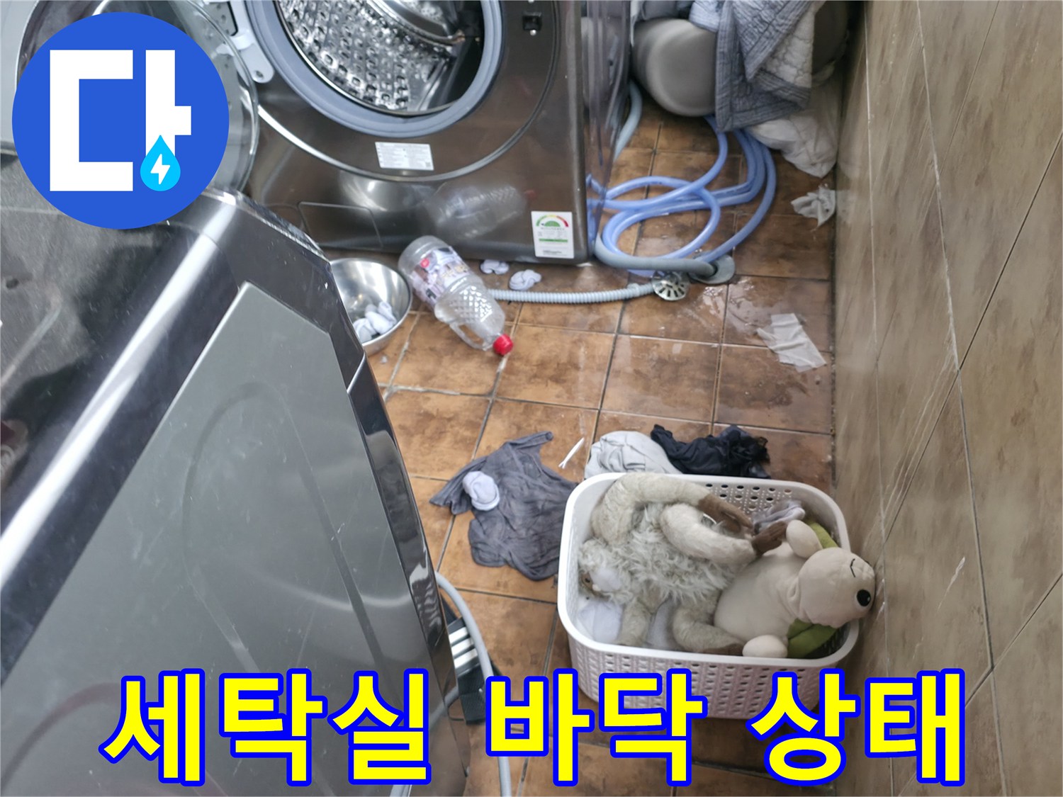 세탁기와 세탁기 배수 호스가 놓인 다용도실 바닥의 모습입니다.
