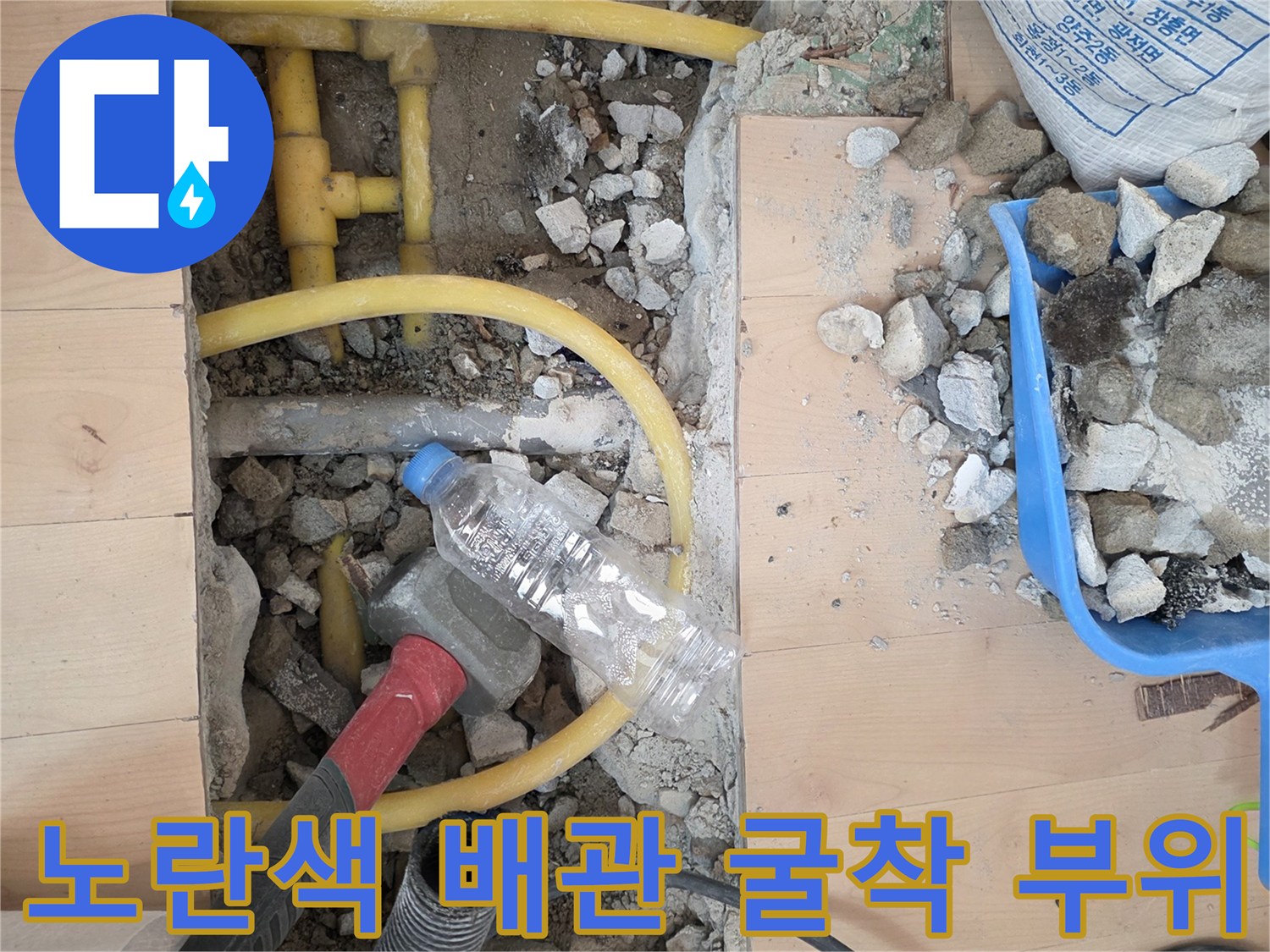 바닥재를 제거하고 노출된 노란색 수도 배관과 주변 잔해물