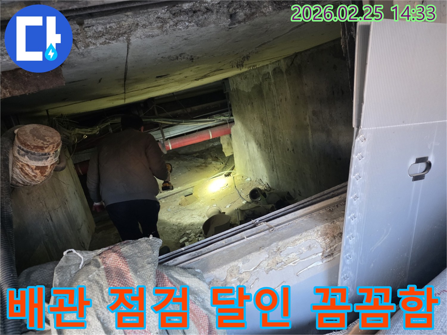 누수 전문 엔지니어가-어둡고 좁은 공간에서-손전등을 비춰가며-배관의 모든 부분을-꼼꼼하게 확인하는 모습입니다.