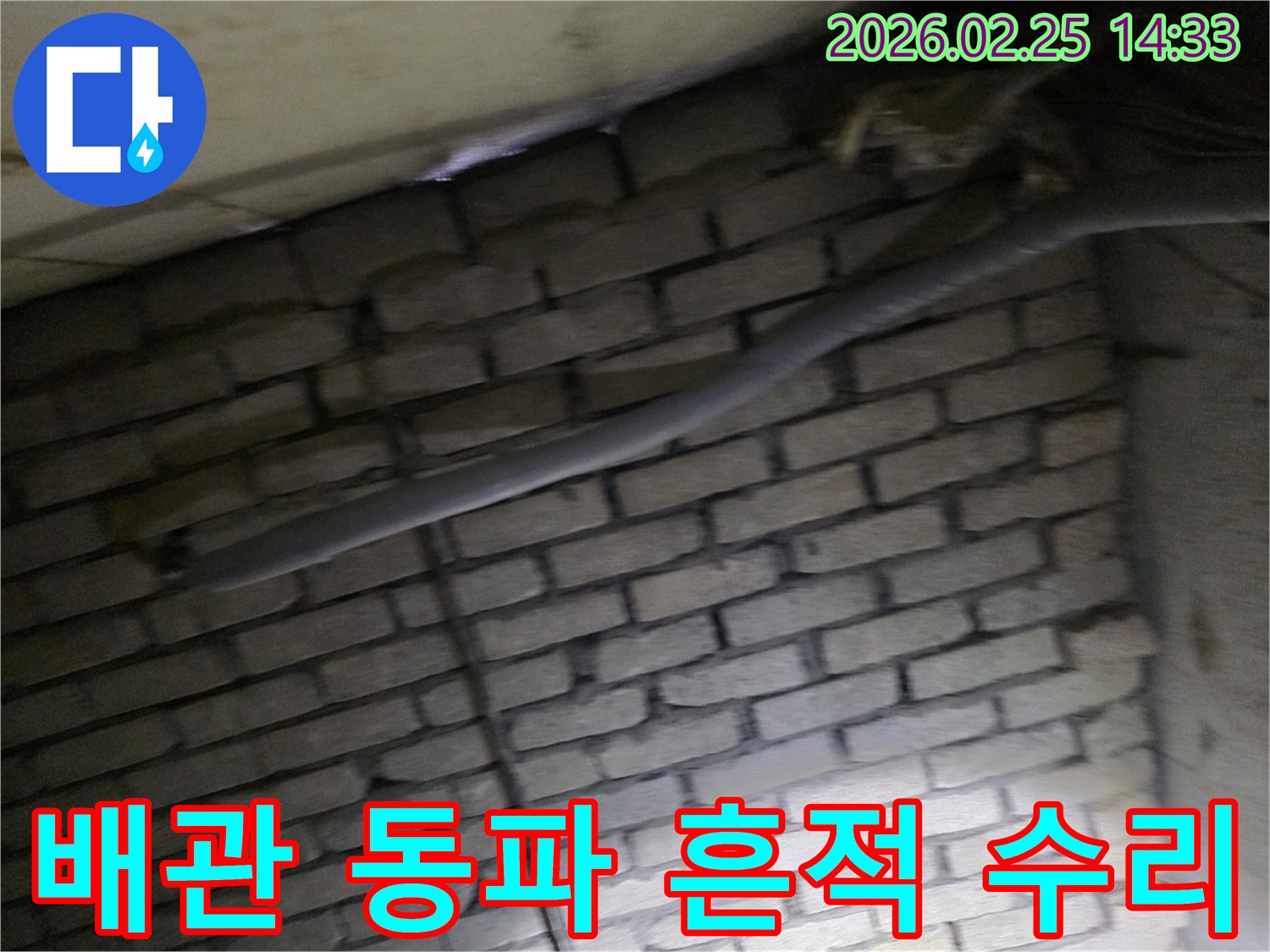 어두운 벽돌 벽면을 배경으로-단열재로 감싸인 배관에서-동파로 인한 누수 흔적을-확인하기 위해 촬영된 현장 이미지입니다.