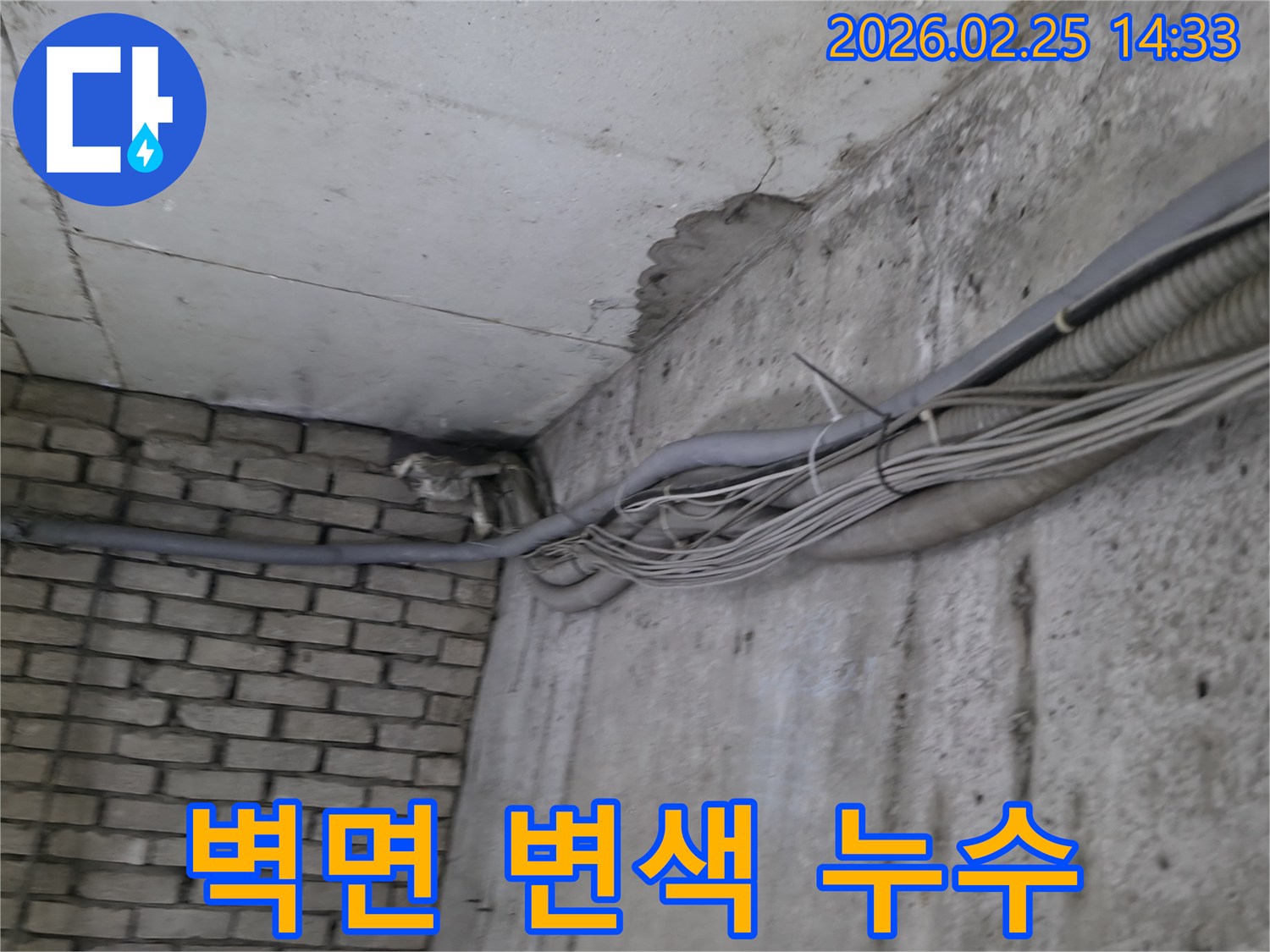 지하 벽면의-콘크리트와-벽돌 벽이 만나는-지점에서-발견된-오랜 누수로 인한-짙은 물자국과-변색 그리고-주변 배관