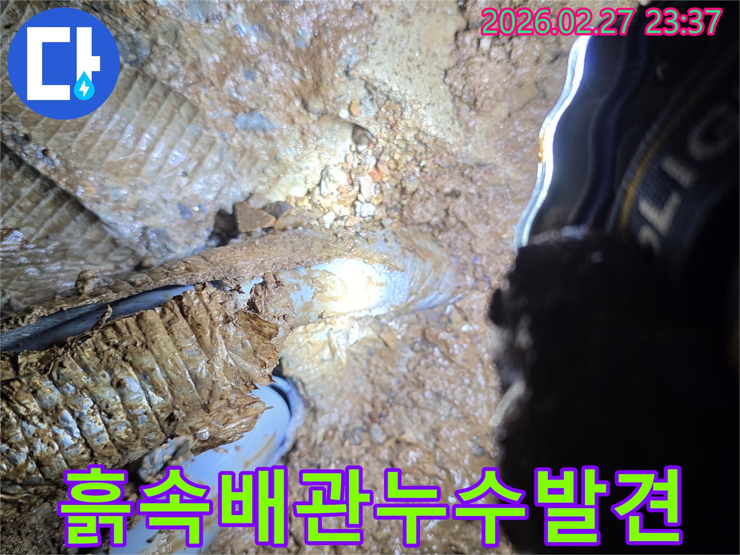 흙과-진흙으로-뒤덮인-지하-현장에서-발견된-배관의-누수-지점을-확대하여-보여주는-사진