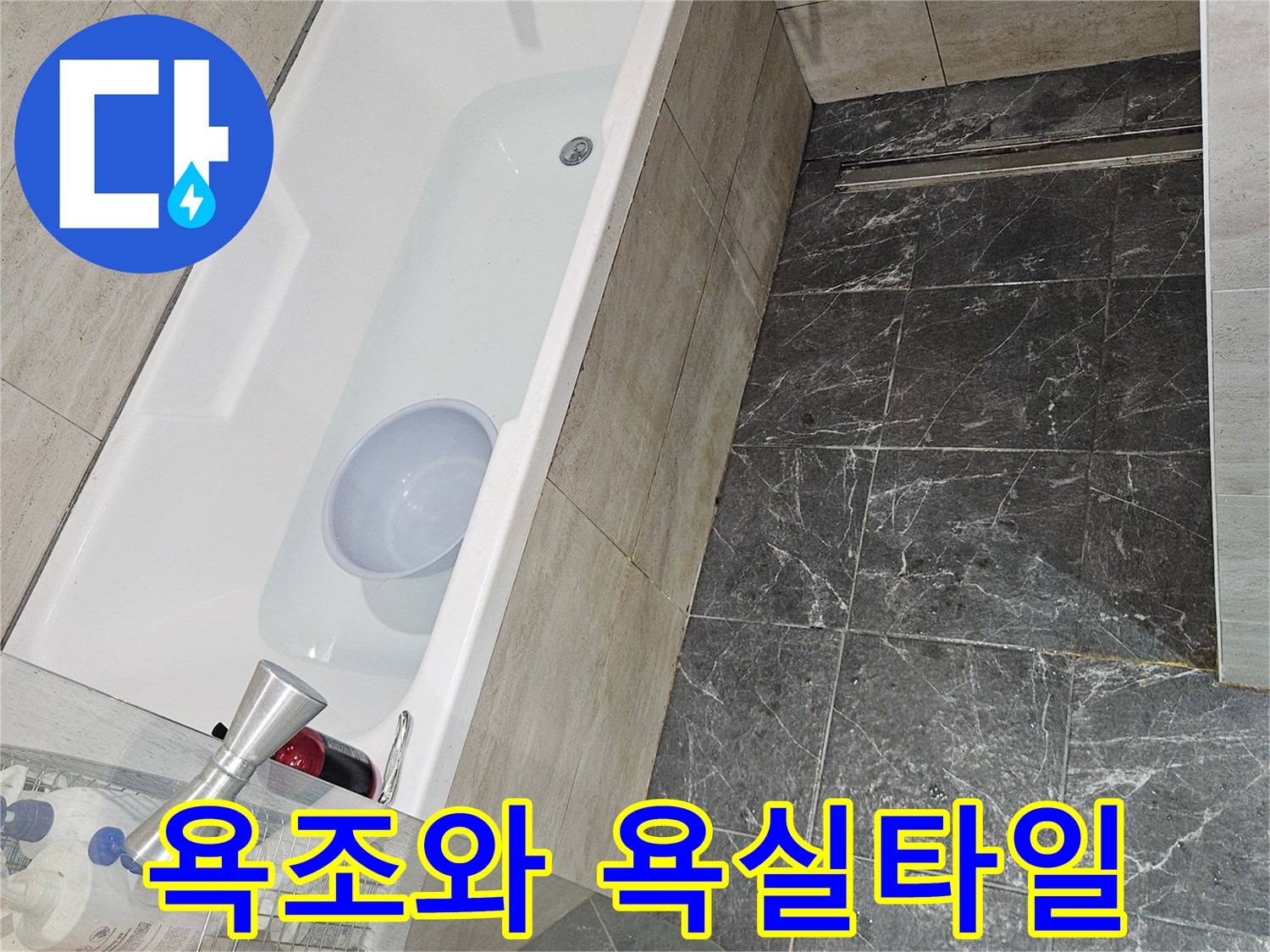 어두운색 타일로 마감된 욕실의 욕조와 수전 모습입니다.