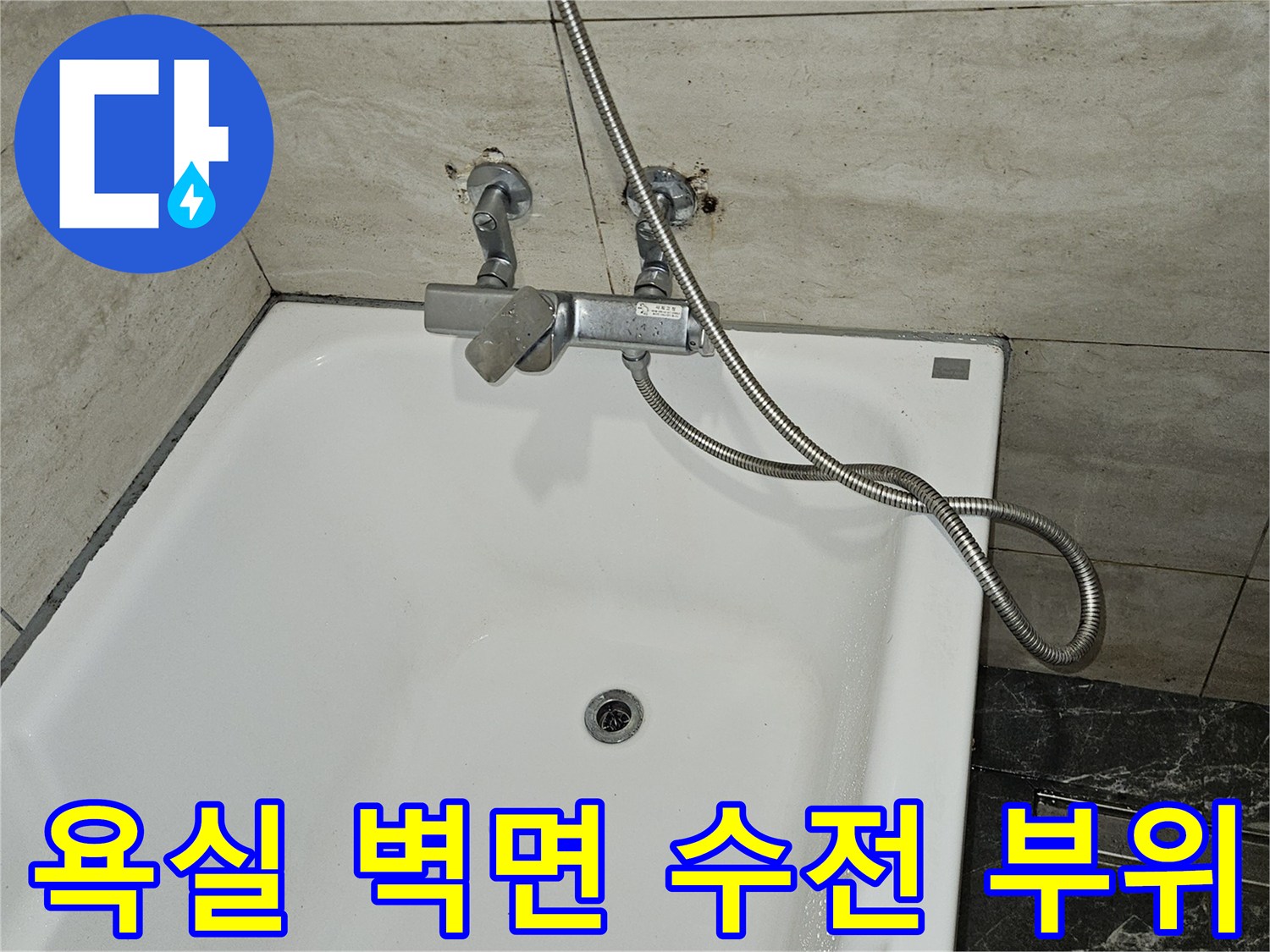 하얀색 욕조 옆 타일 벽면에 설치된 급수 밸브와 호스