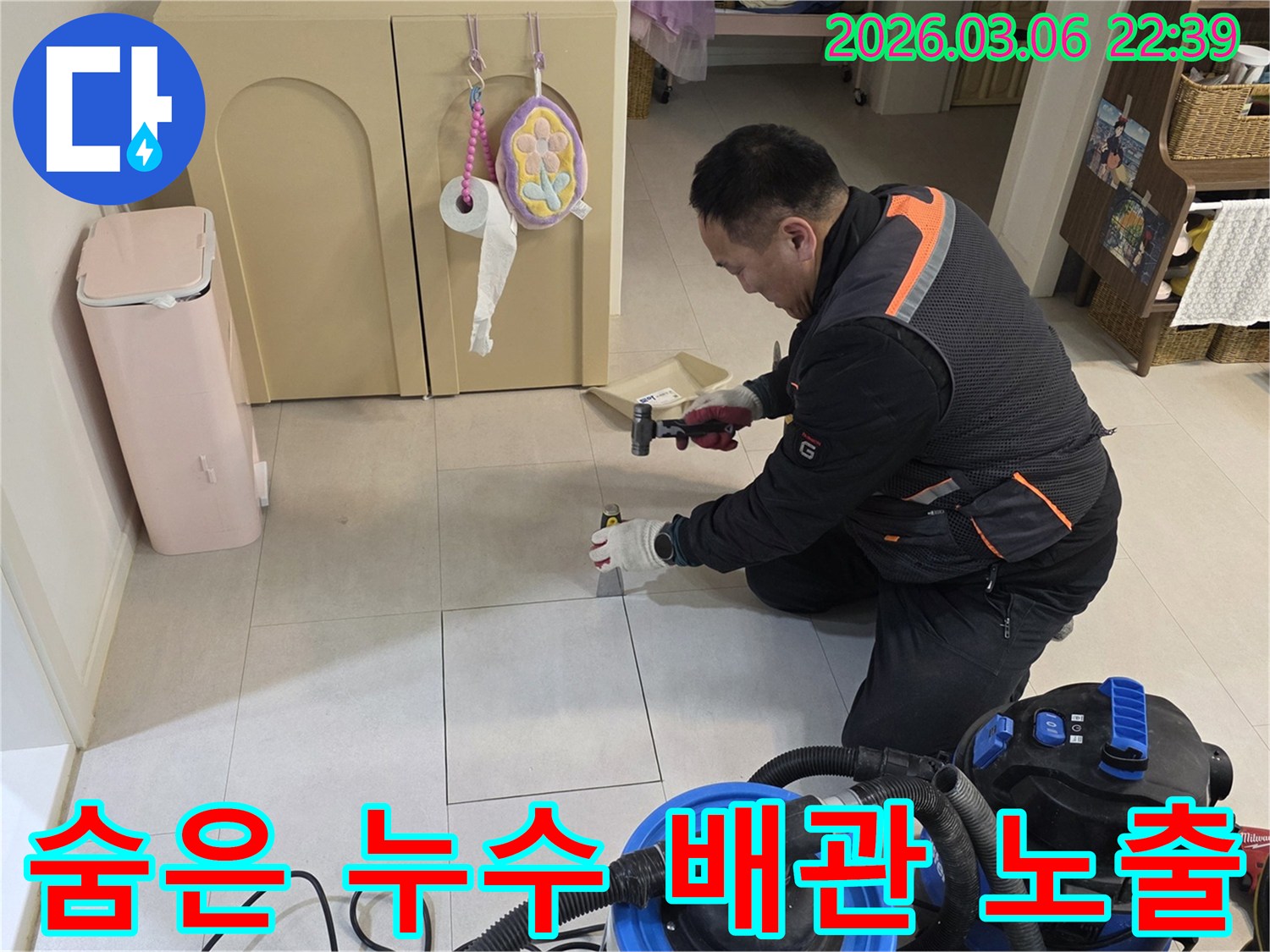 누수 전문가가-바닥 아래 숨겨진 배관을 점검하고자-타일 제거 작업을 진행하고 있습니다.