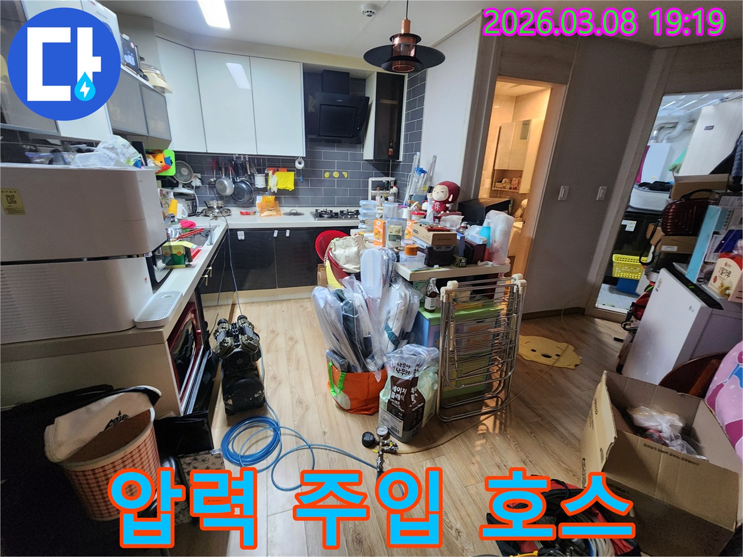 누수-탐지를-위해-배관에-연결된-파란색-호스와-압력-게이지가-주방-바닥에-놓여있는-장비-설치-현장