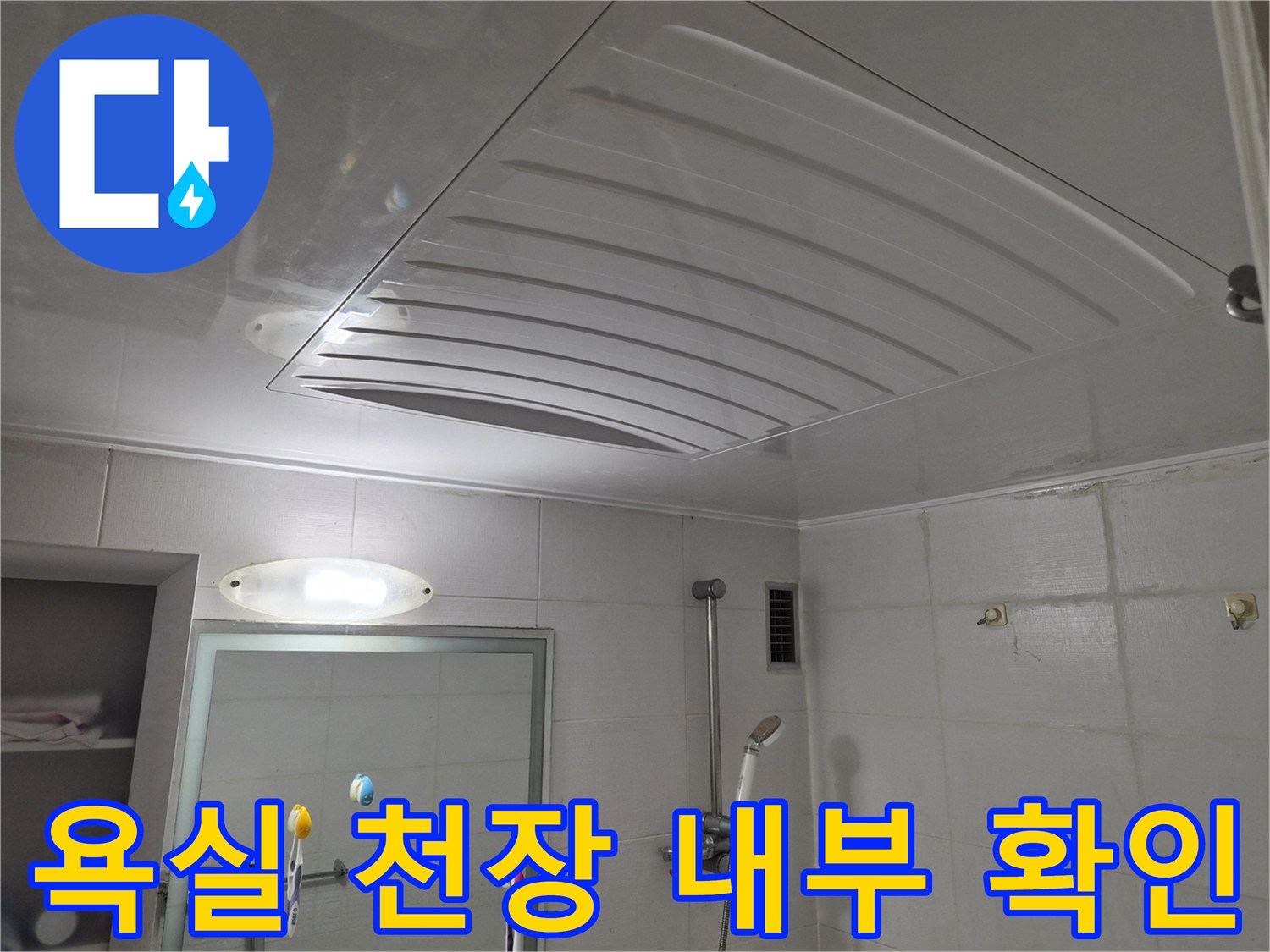 욕실 천장 패널을 들어 올려 배관을 살펴보는 작업 현장