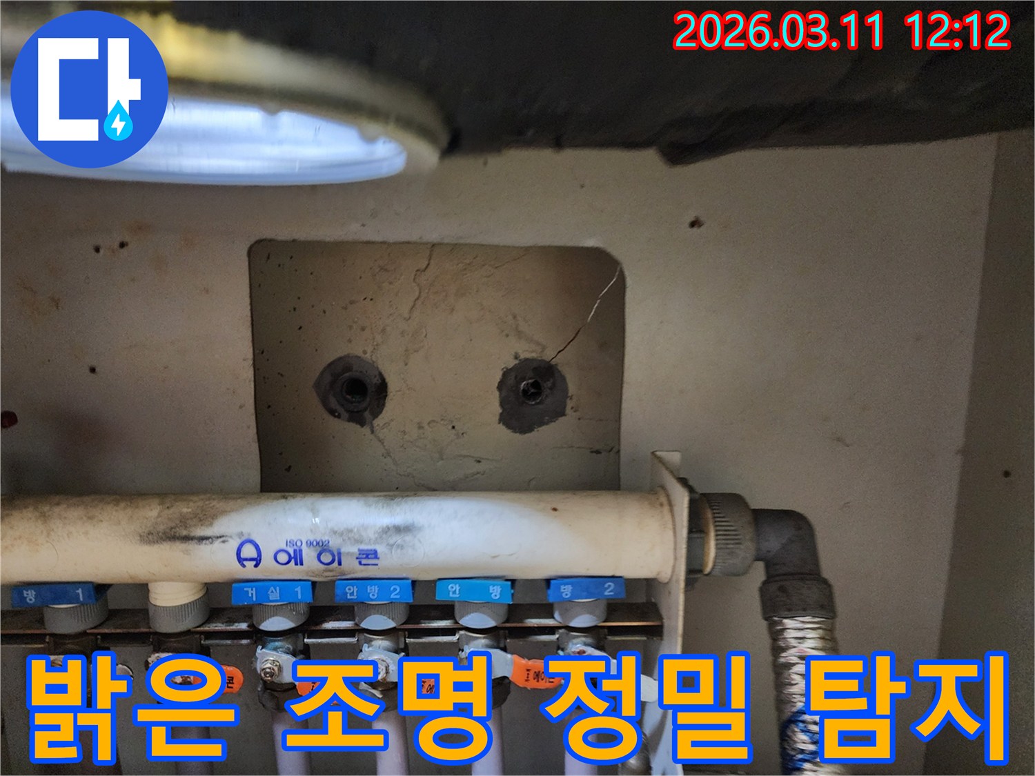 밝은 조명 아래에서-보일러 분배기-및-주변 배관의-미세한 누수 흔적을-정밀하게 탐지하는-누수 전문가의-작업 현장