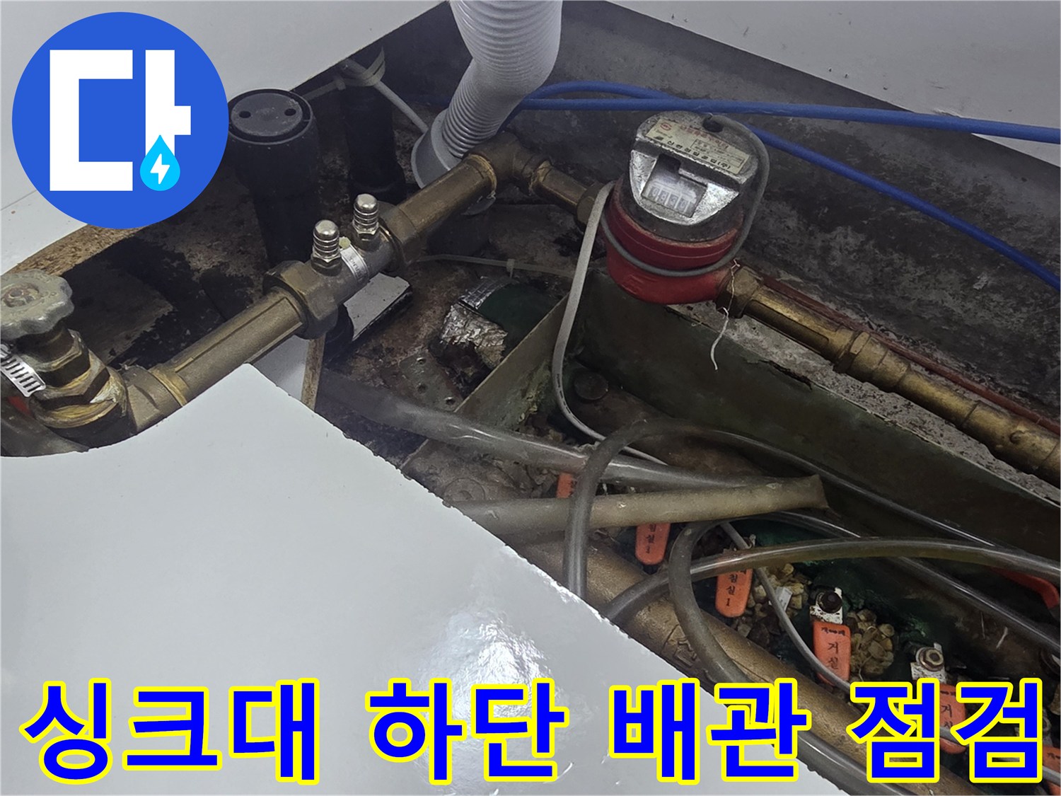 주방 싱크대 아래 수도 계량기와 연결된 배관들