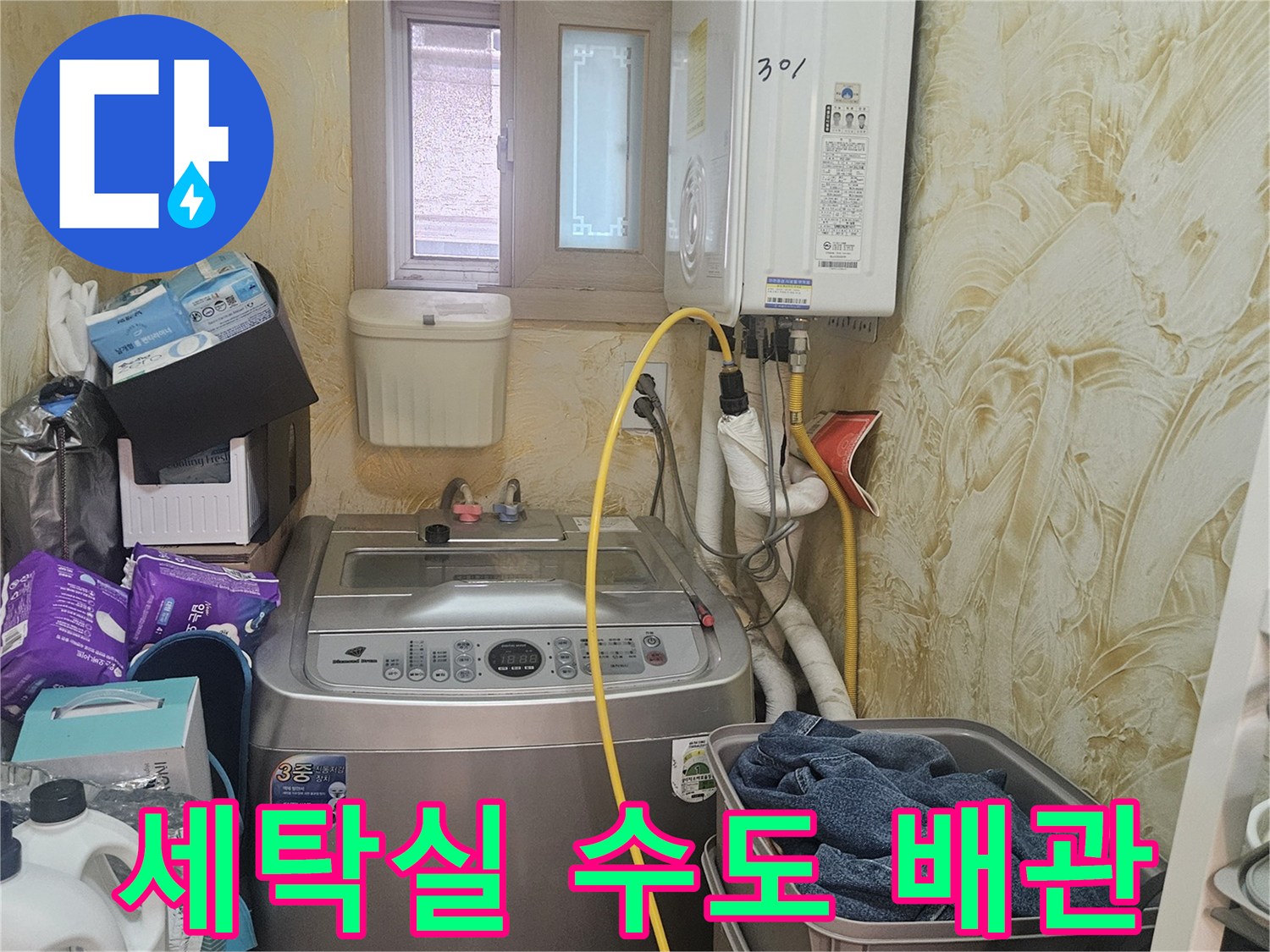 세탁기 옆으로 지나가는 노란색 호스와 배관 연결부