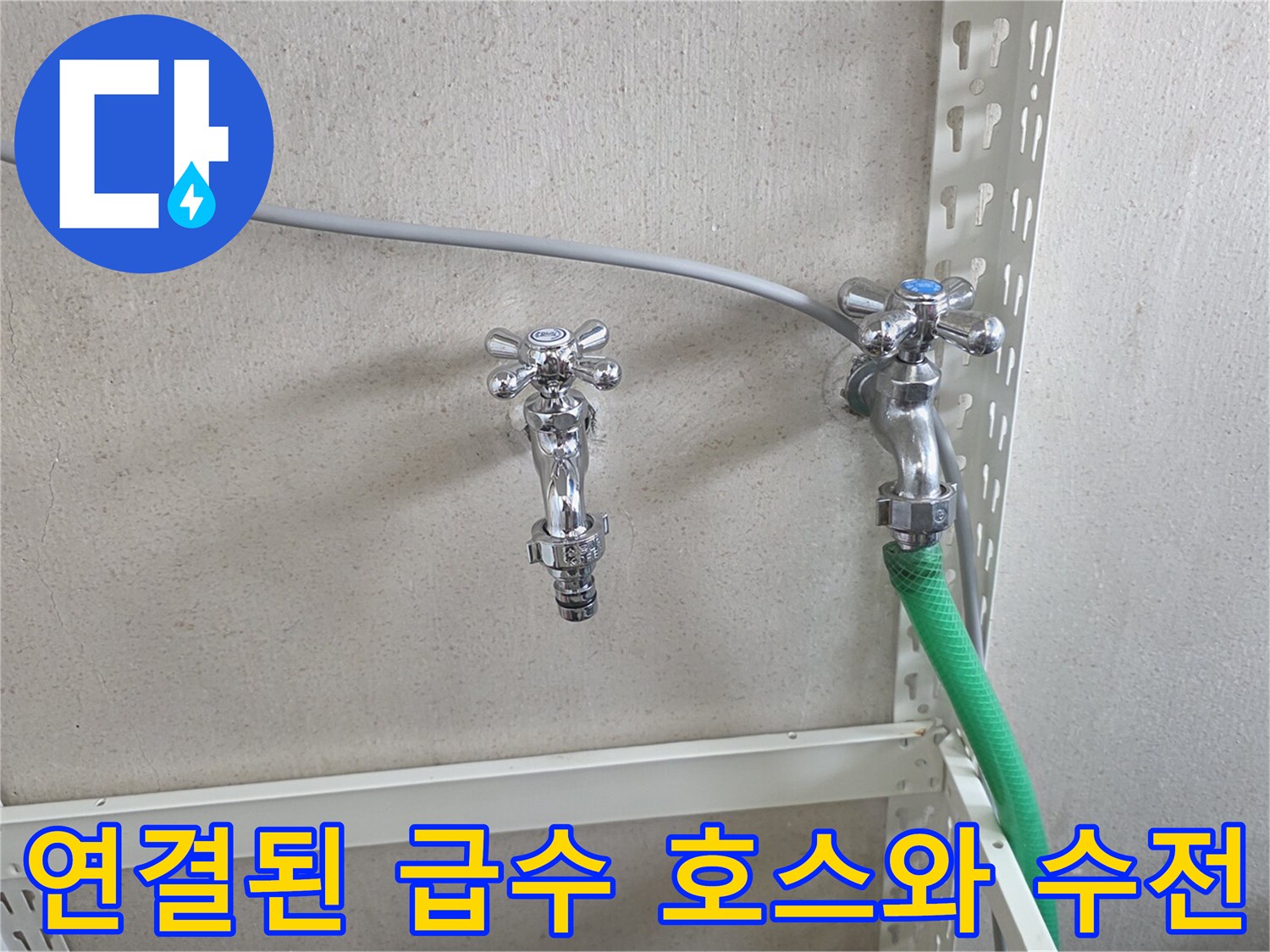 금속 수전과 초록색 호스가 연결된 벽면 배관 모습