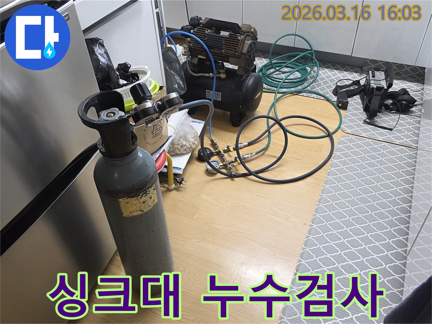 싱크대 배관 누수 여부를 확인하기 위해-질소 가스통과 압축기를 연결하여-압력 테스트를 준비하는 현장입니다